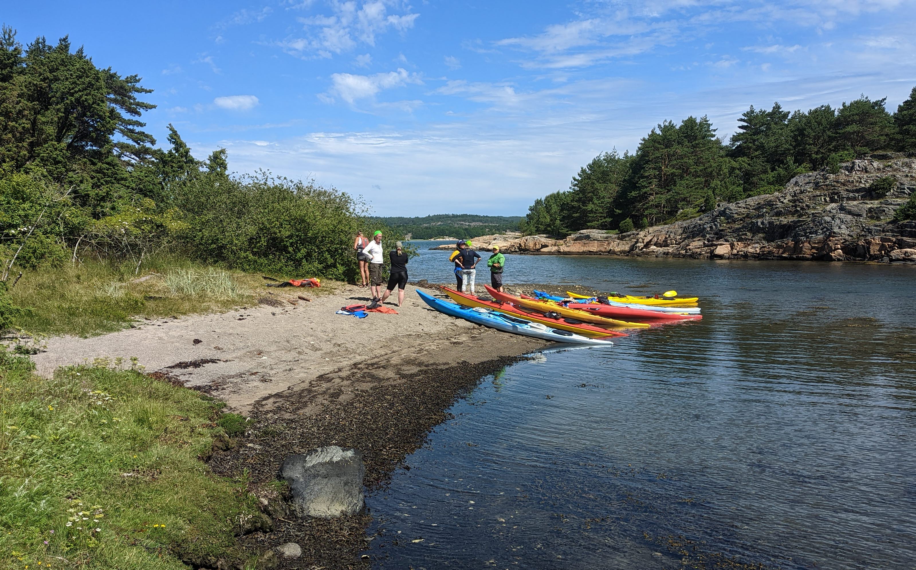 A group of kayakers land on a scenic and leafy beach in the Bohuslän archipelago; Balanspunkten – Kayak in Grundsund 
