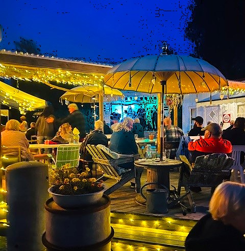 Colorful parasols and guests in the evening on the terrace, Nössemark Camping, Café, Guest Harbor & Cabins