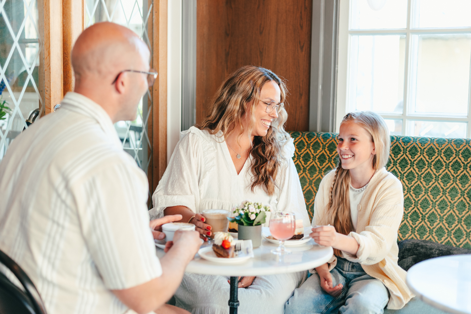 A happy family with a mother, father, and daughter enjoying delicious pastries and drinks at Conditori Nordpolen
