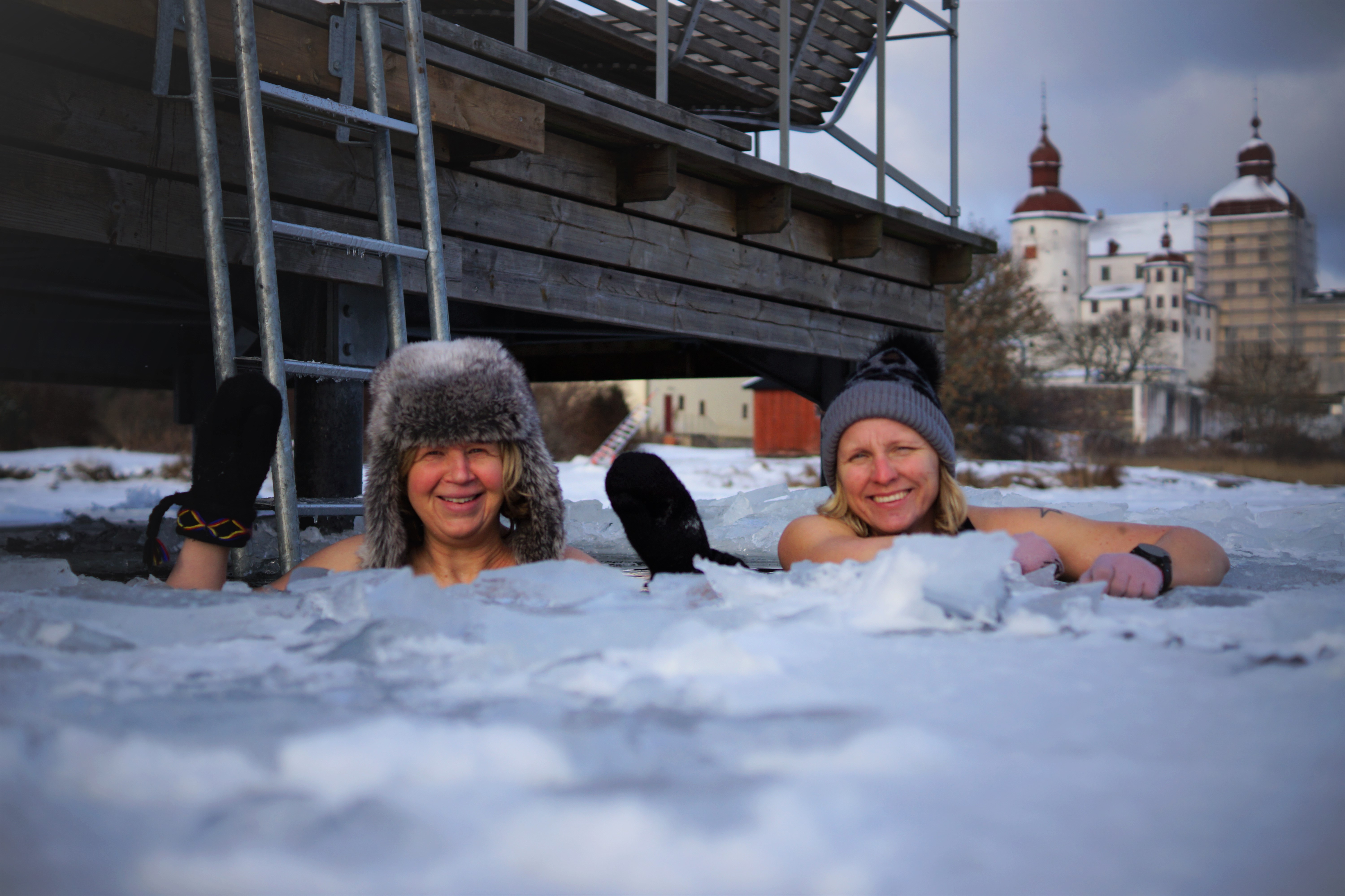 Two women taking a swim in an ice hole by Läckö castle