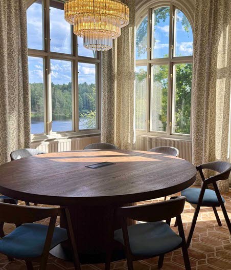 Large round conference table with an impressive chandelier above in a beautiful room at Karstorp Säteri