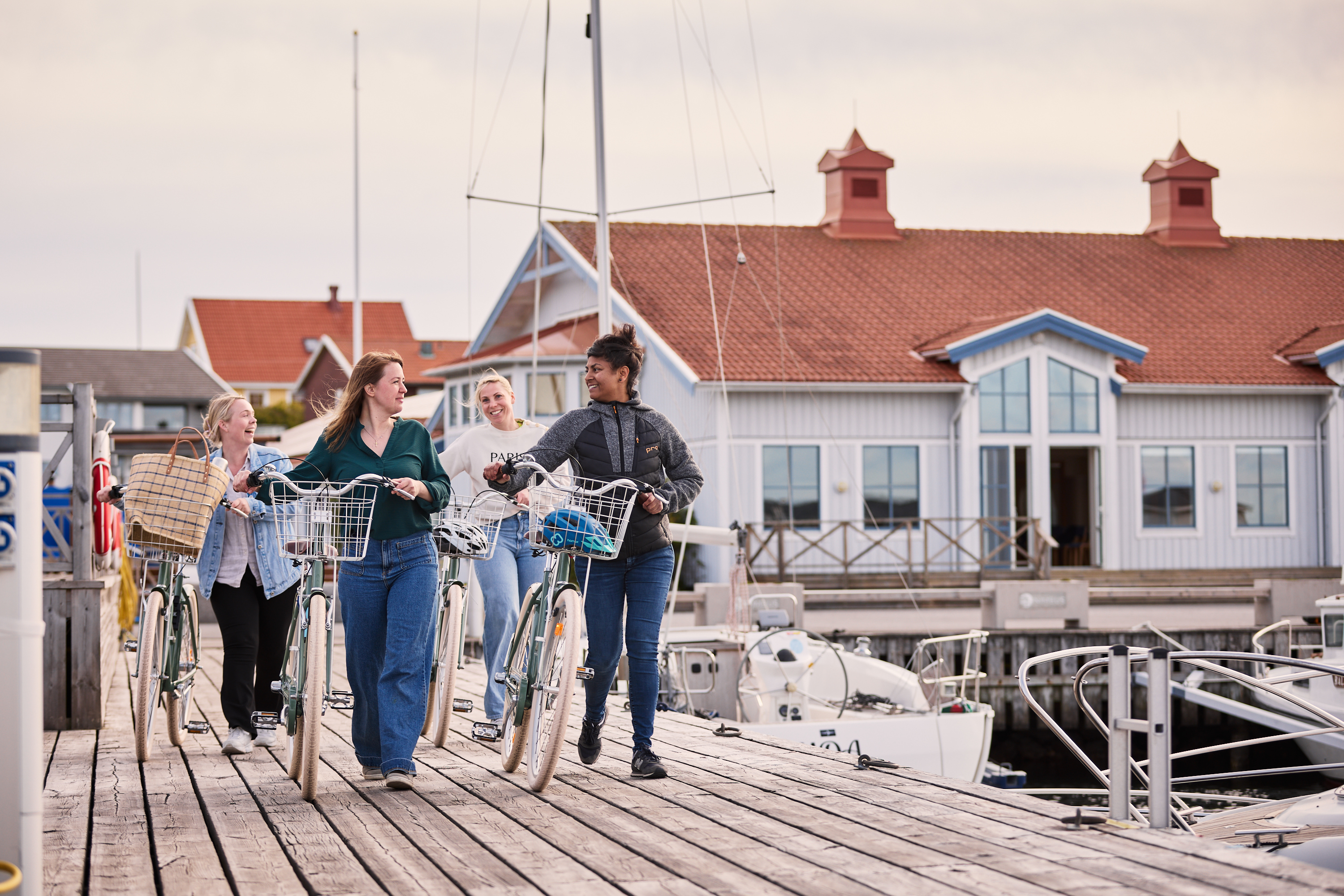 A group of people are walking their bikes on a pier.
