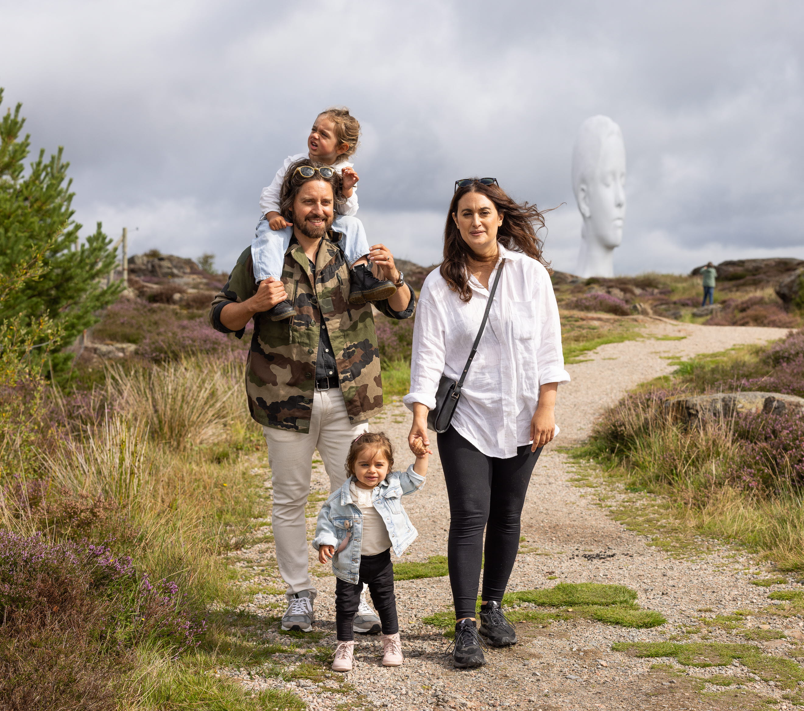 Family walks in a sculpture park out in nature.