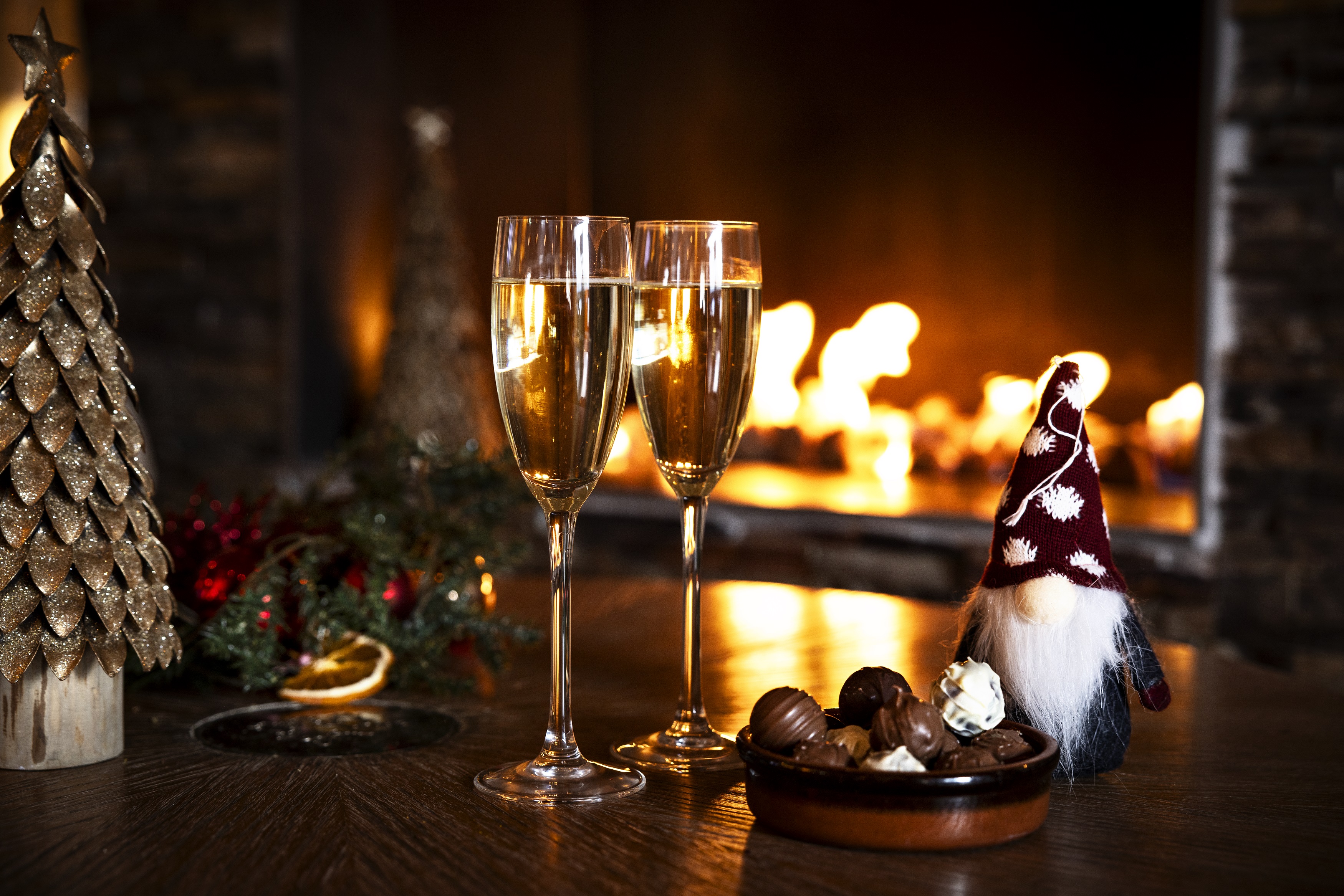 Two glasses of sparkling drink next to a bowl of pralines.