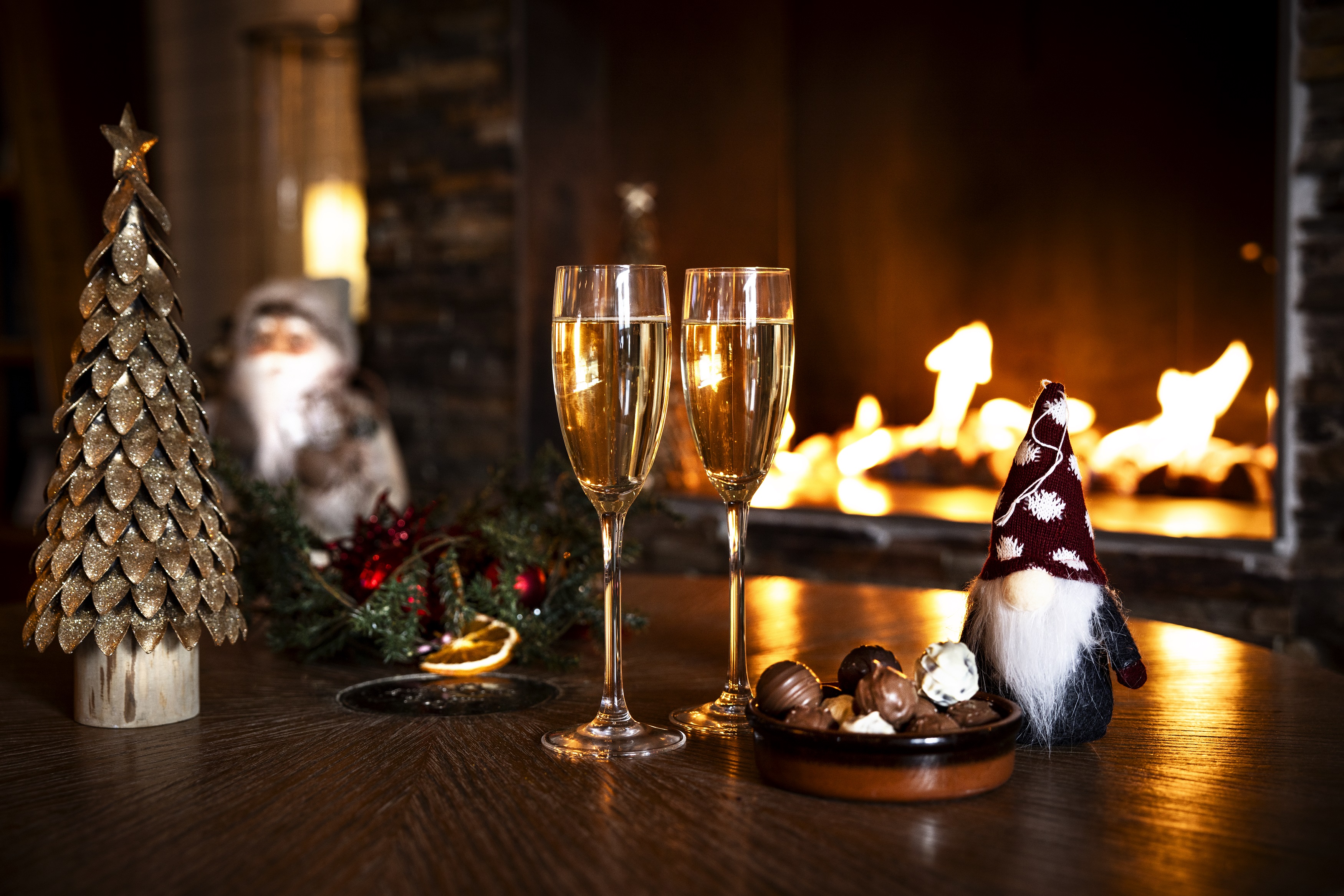 Two glasses of sparkling drink next to a bowl of pralines.