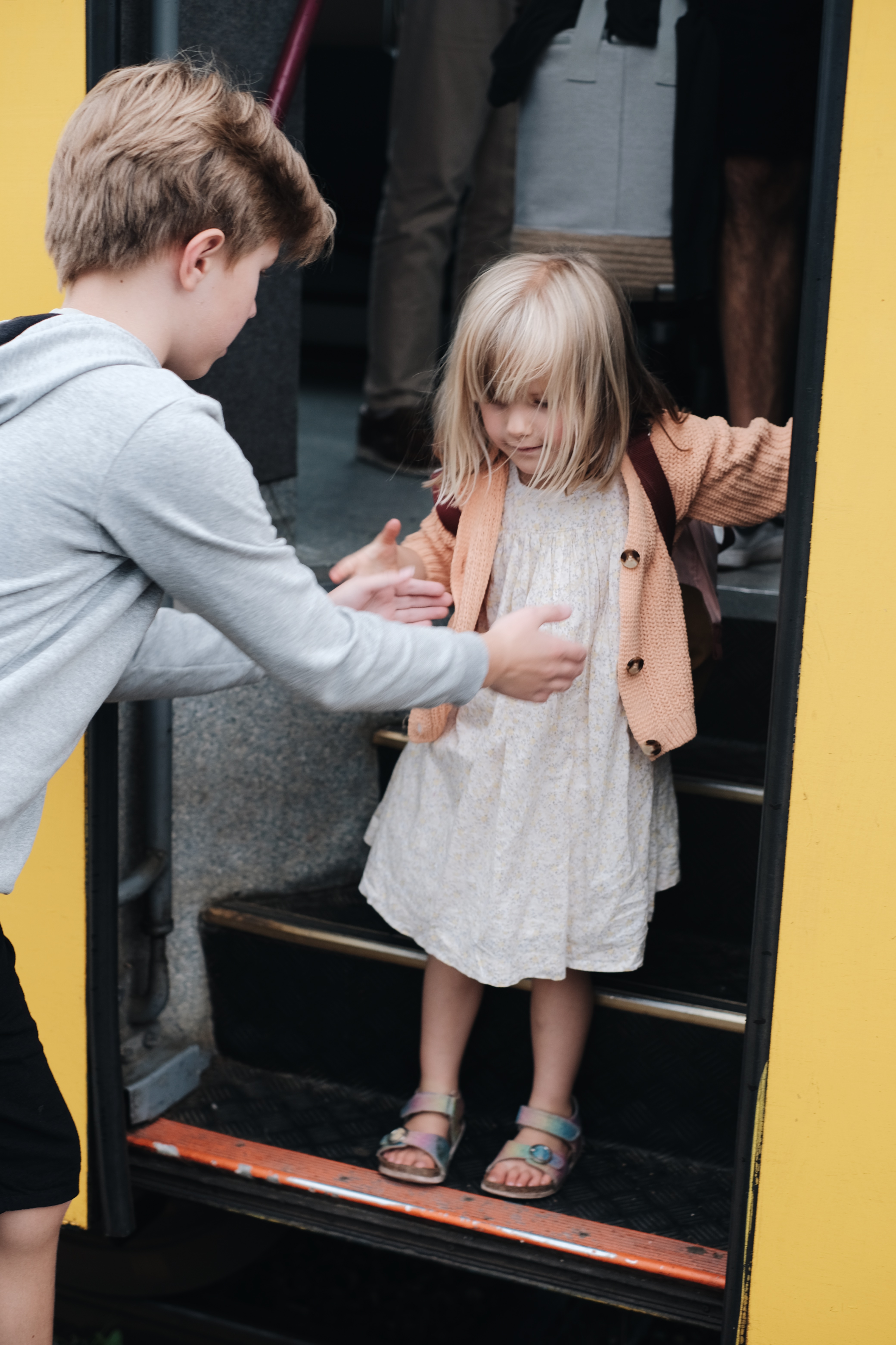 A boy helps a child down a flight of stairs.