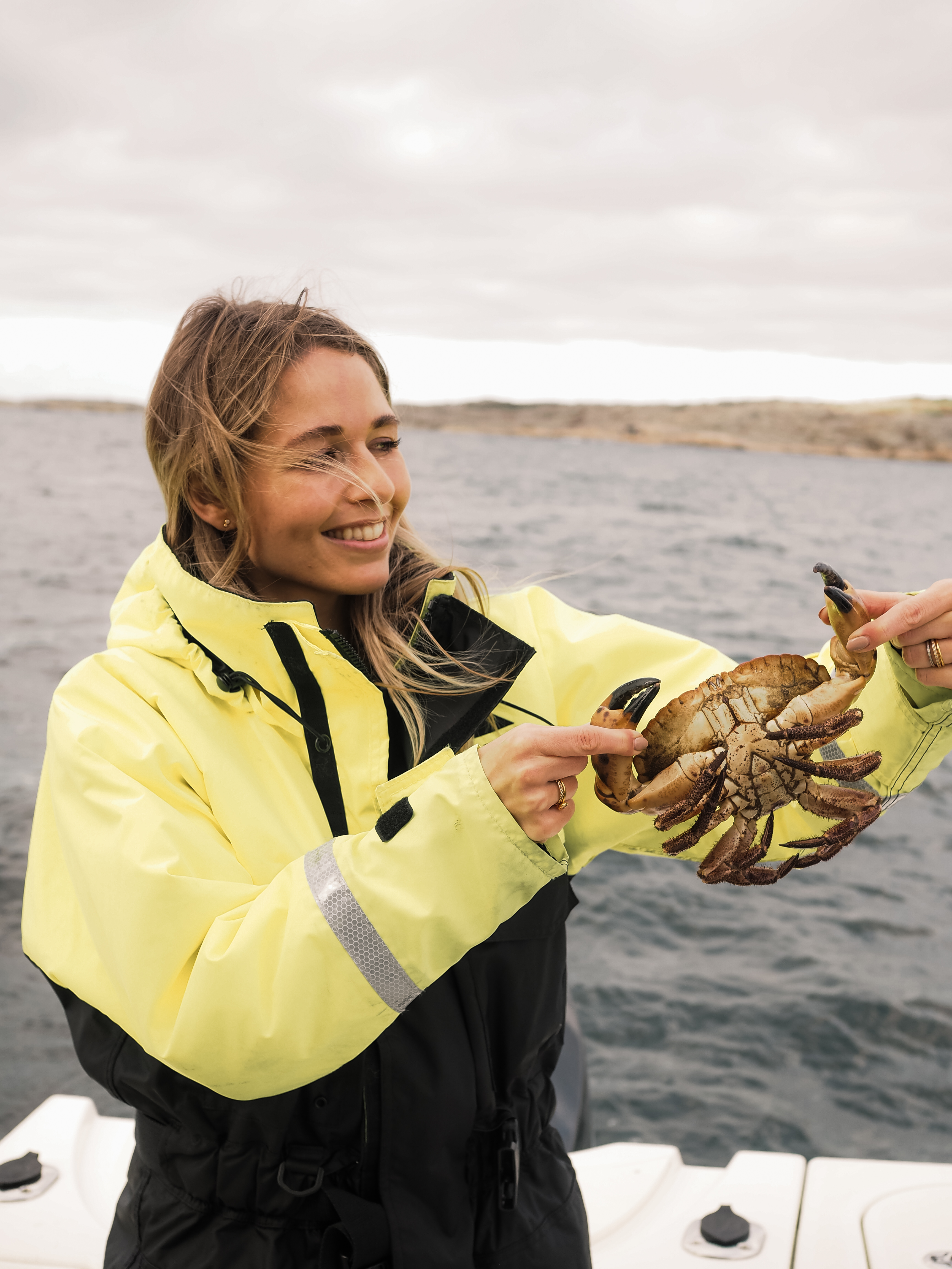 A woman is holding a crab on the boat