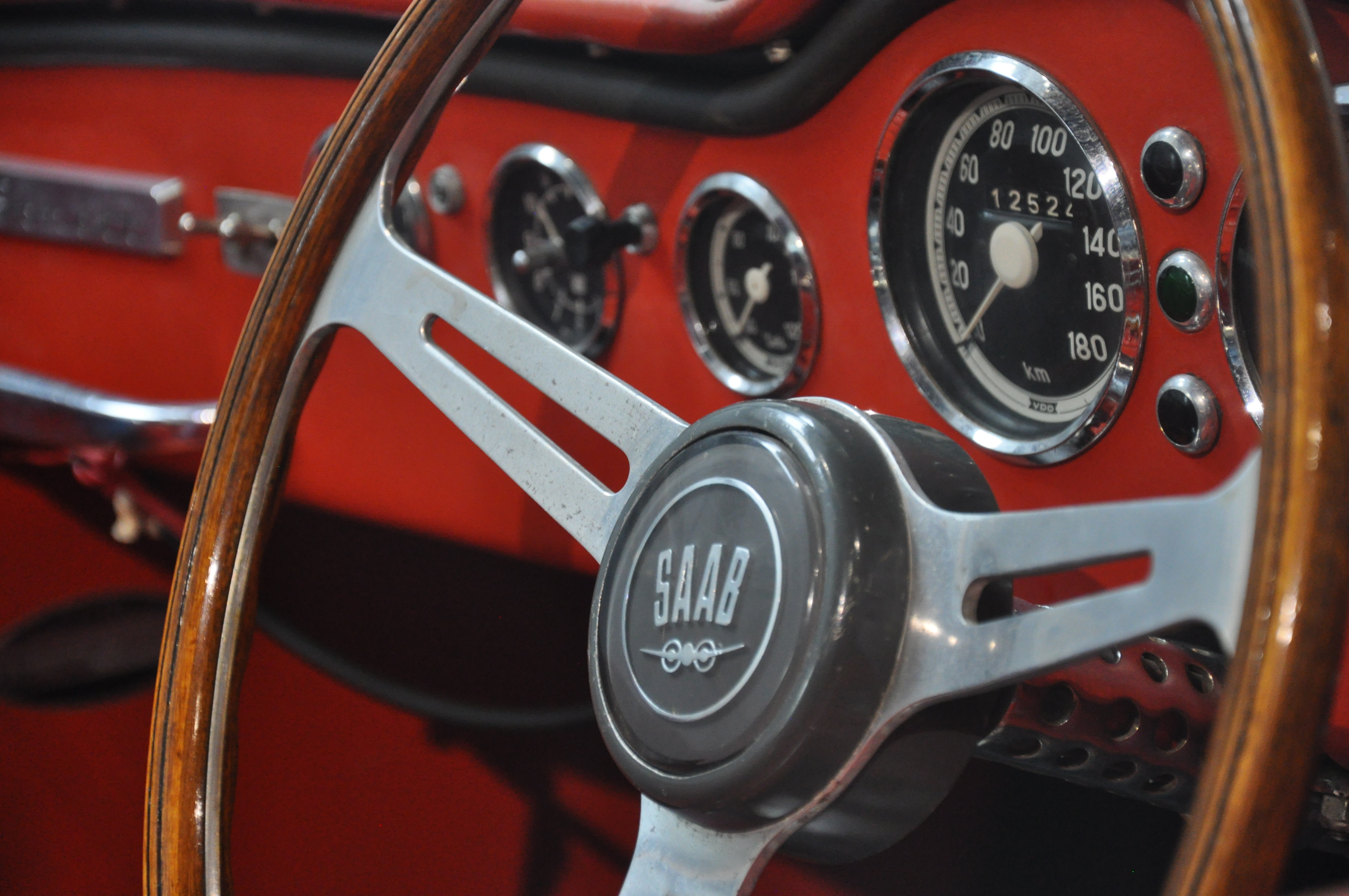 Closeup of a steering wheel of a car with the Saab logotype