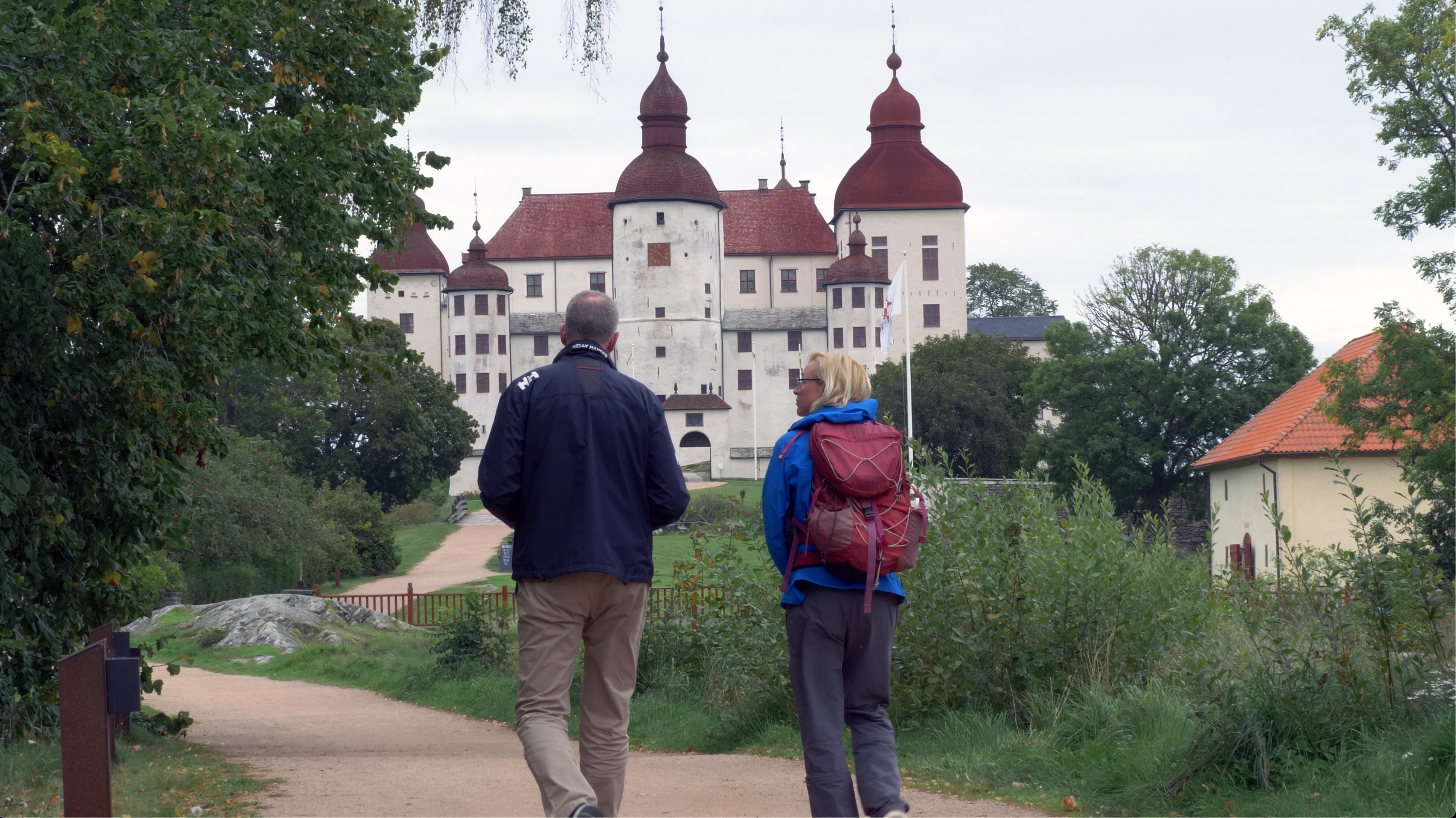 Two people walk outside Läckö Castle.