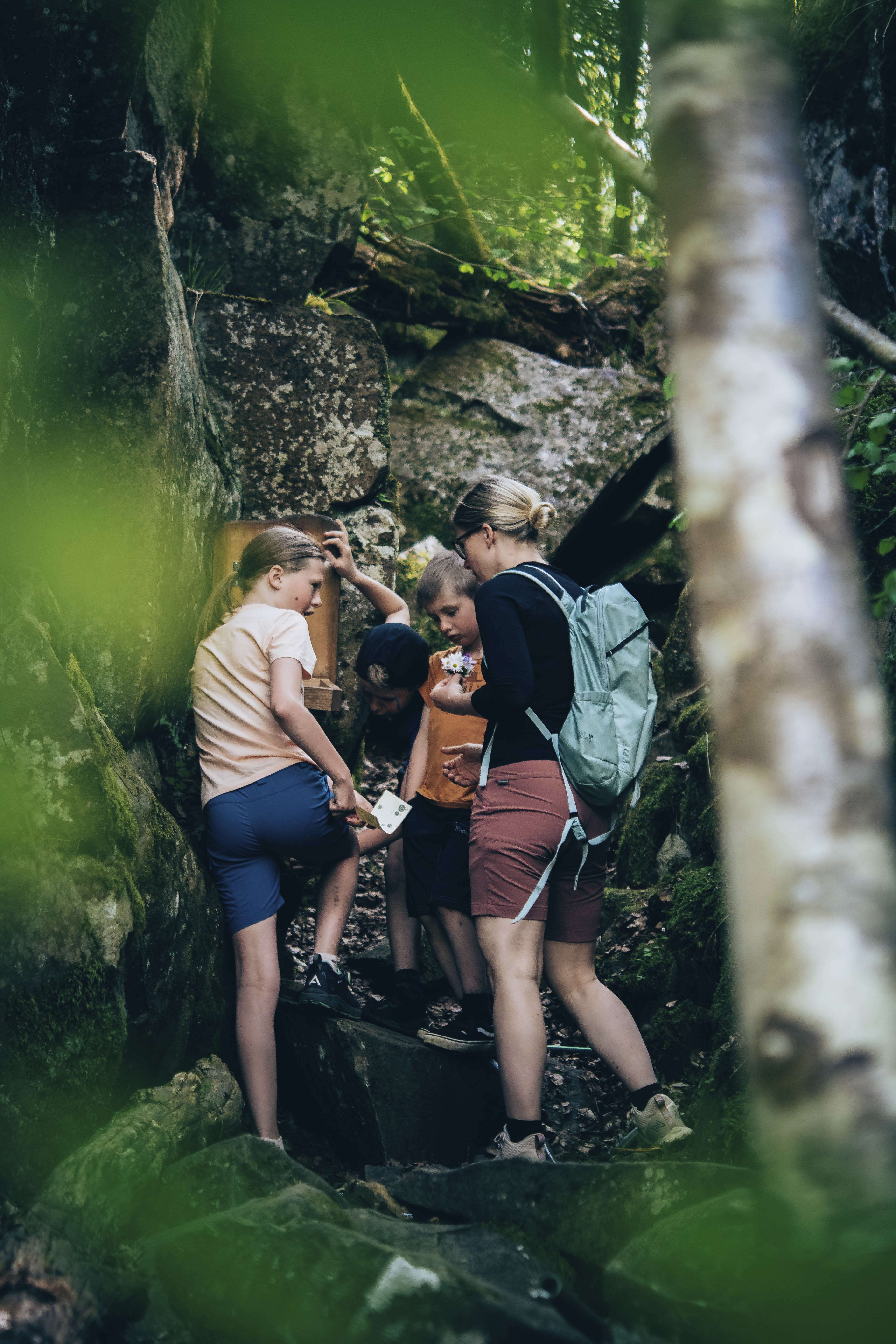 Mother and child walking in the forest standing by boulders