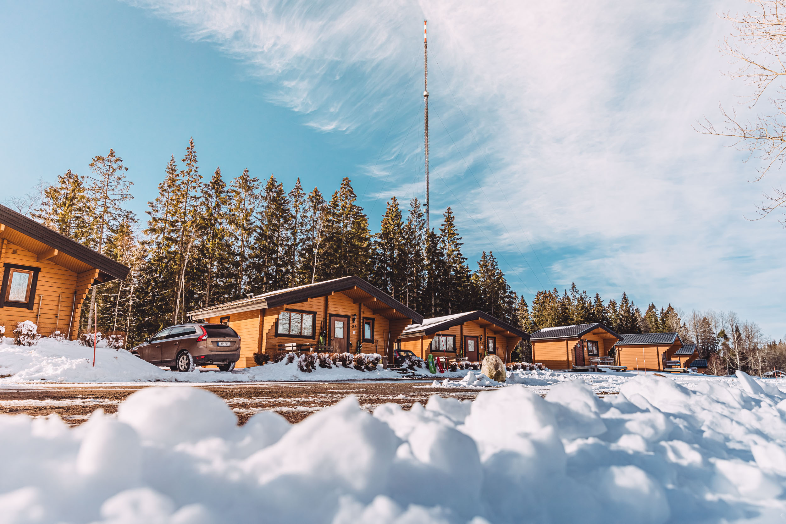 Cabins standing in a row under a clear blue sky in a winter landscape.
