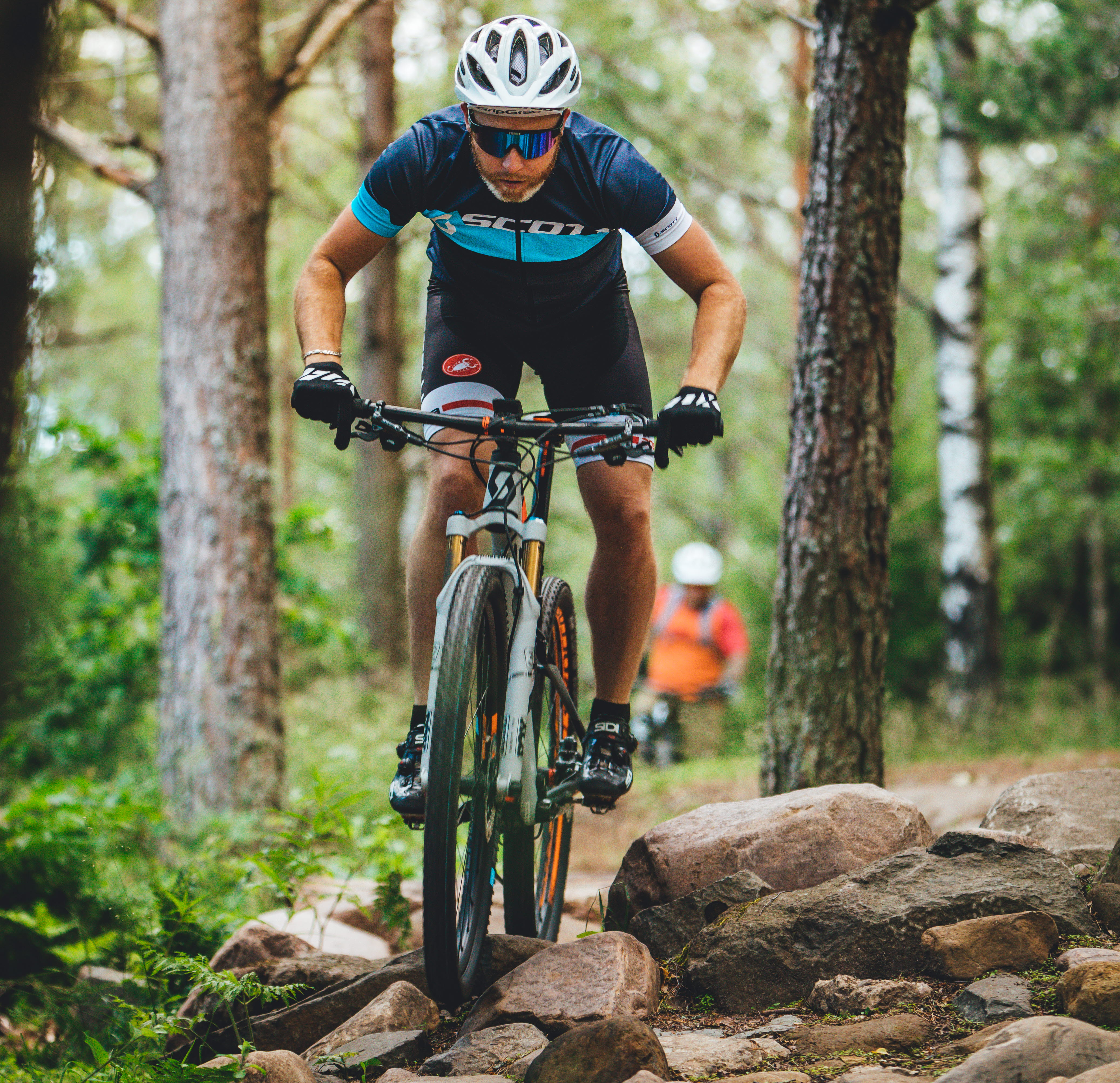 A man rides a mountain bike over rocks in the forest
