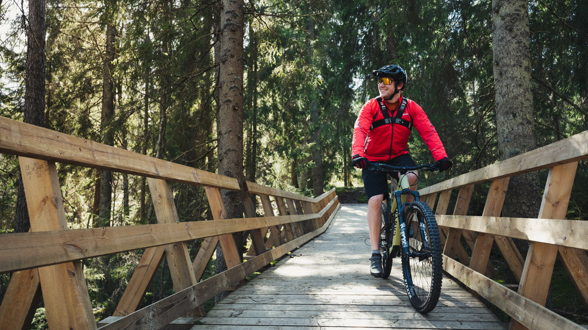 You ride a mountain bike on a wooden bridge built in the forest