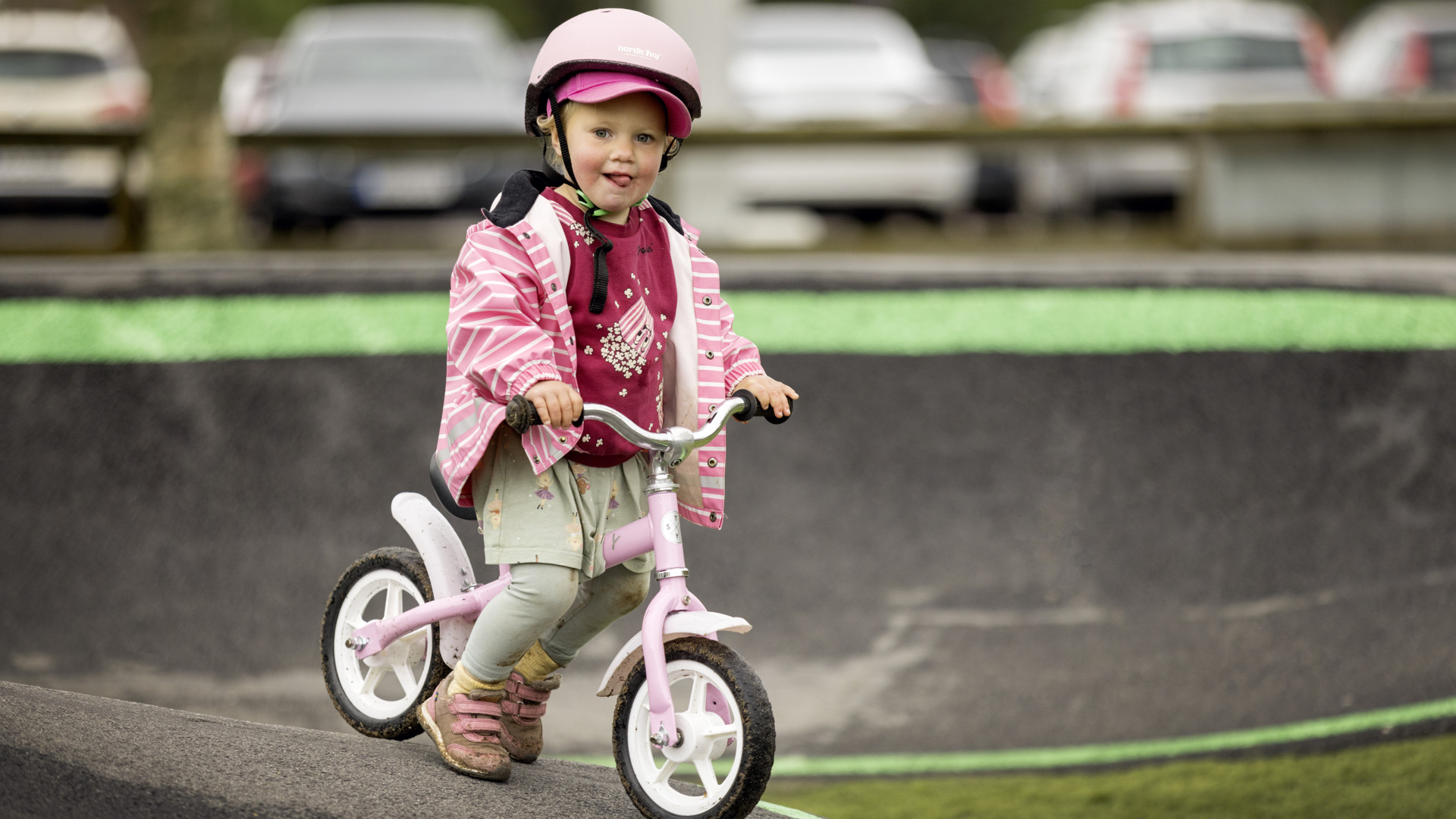 Little girl in pink clothes cycling in Billingen's pump track with her pink bike.