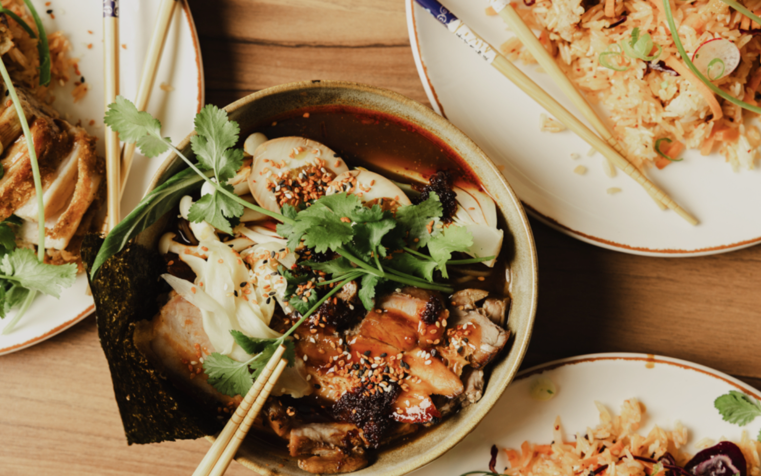 Several plates of different dishes on a wooden table