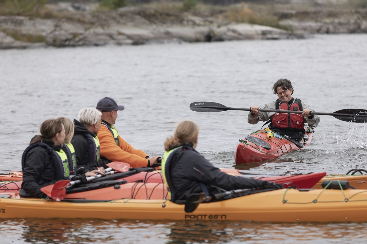 Woman shows a group how to kayak.