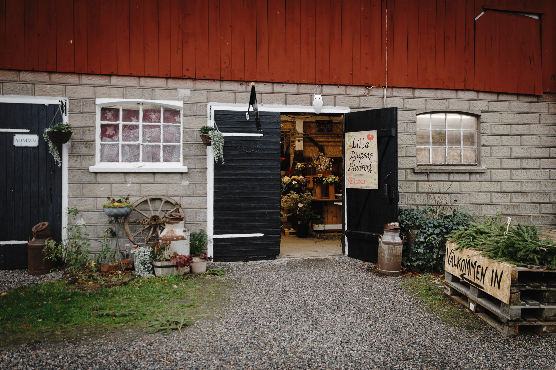 A barn with black doors. One of them is open and inside one can se a shop.