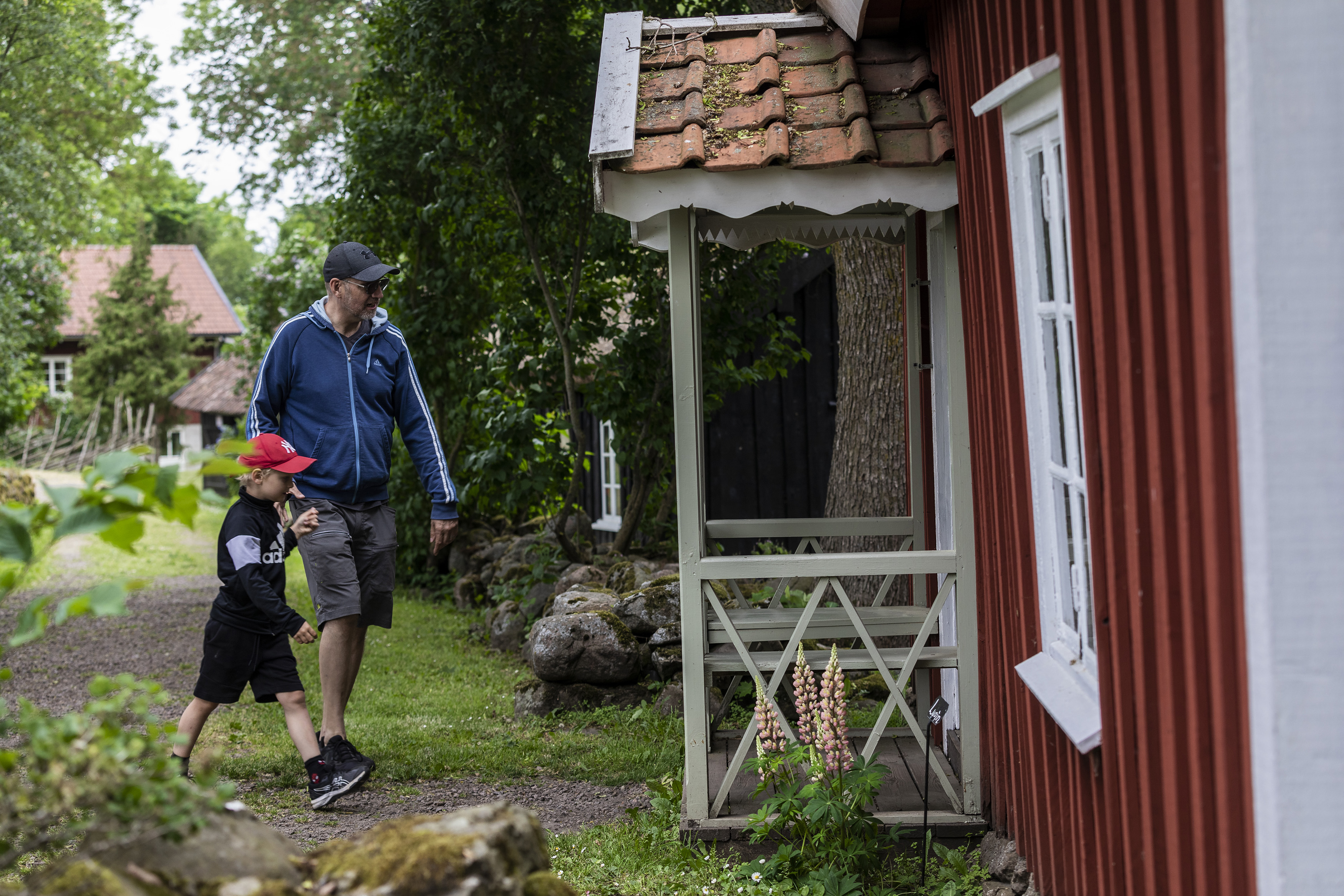 Dad and a boy are on their way into a red cabin.