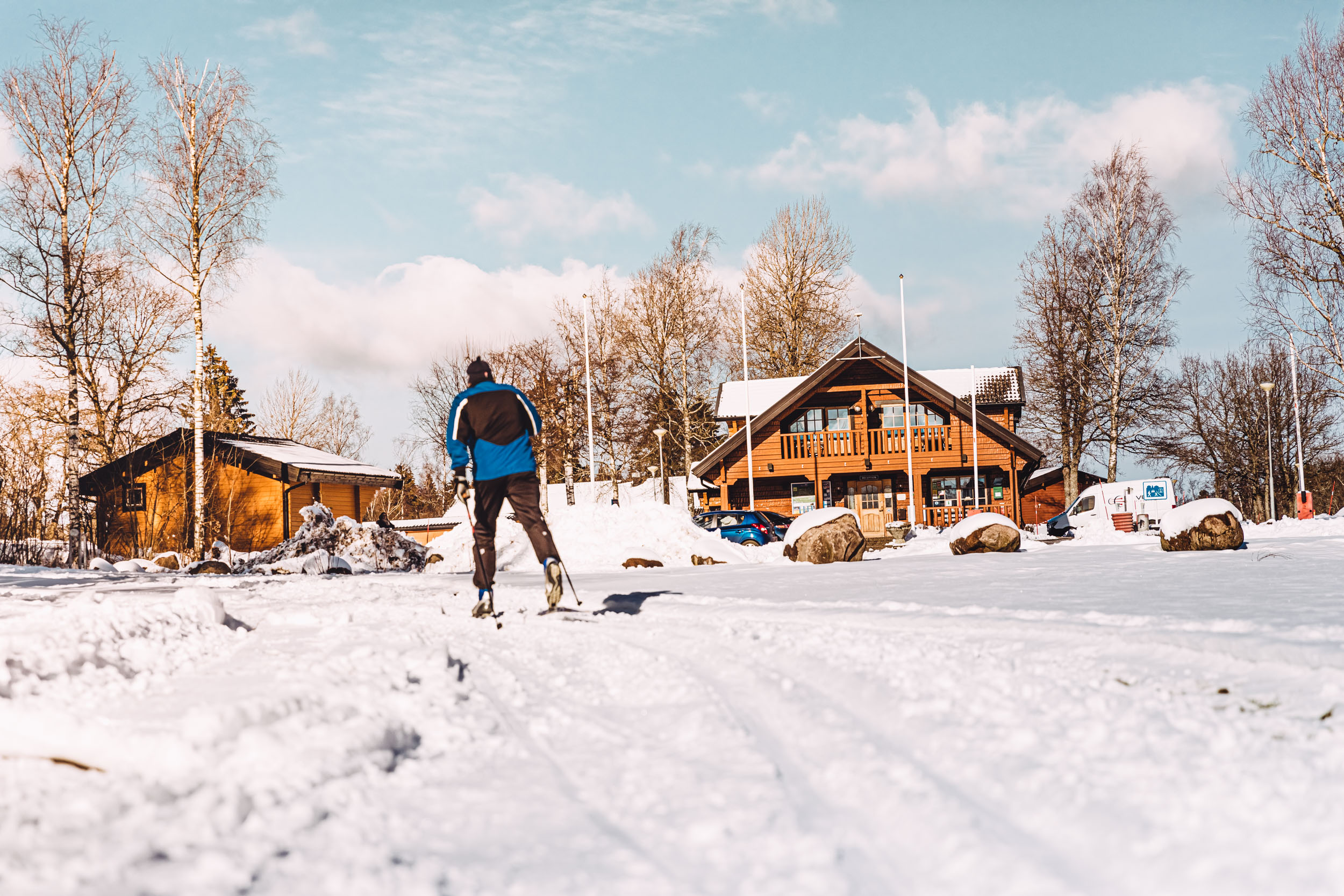 Man cross-country skiing, in the background you can see some cabins on the campsite.