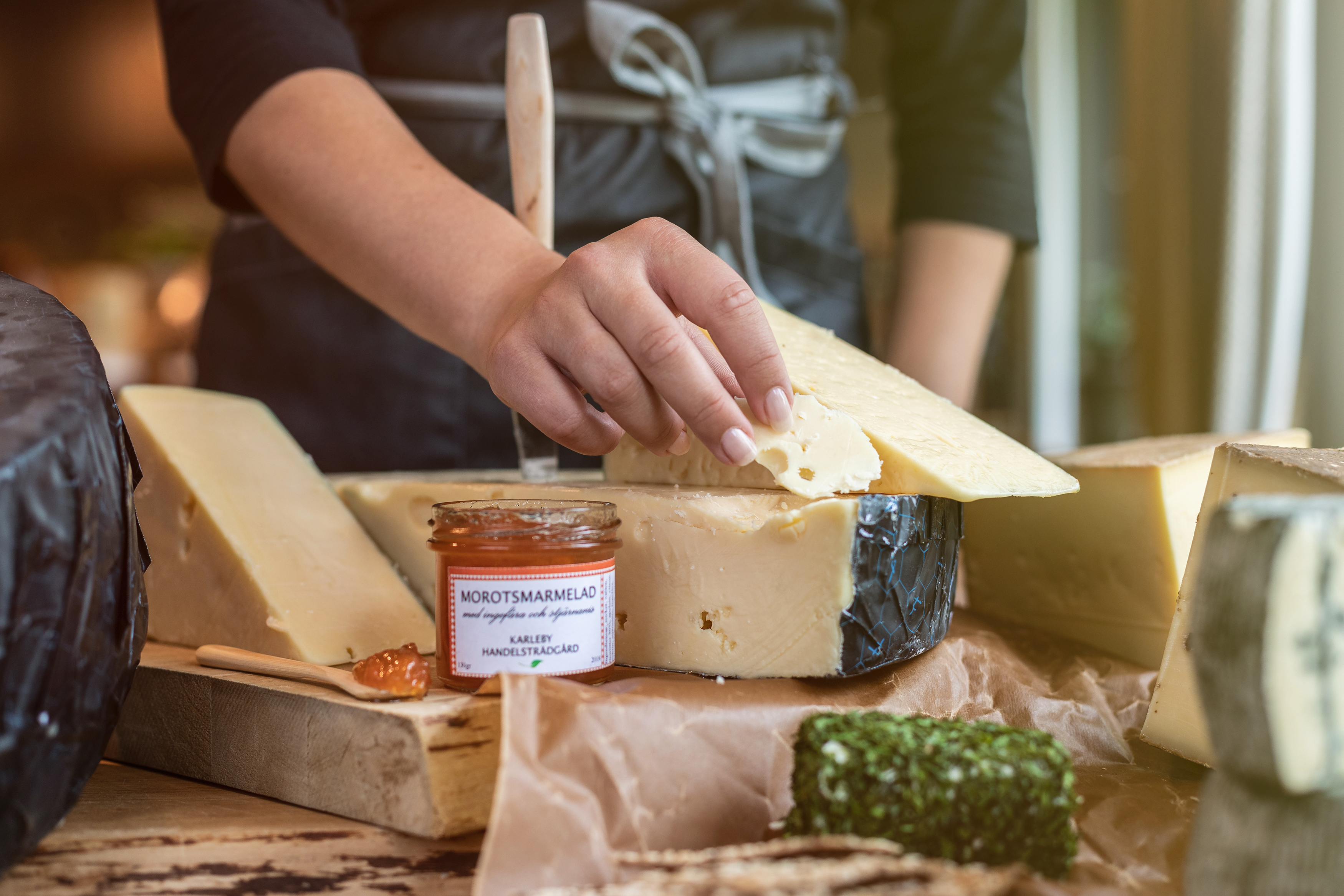 Different cheeses and marmalades. A hand taking a piece of cheese.