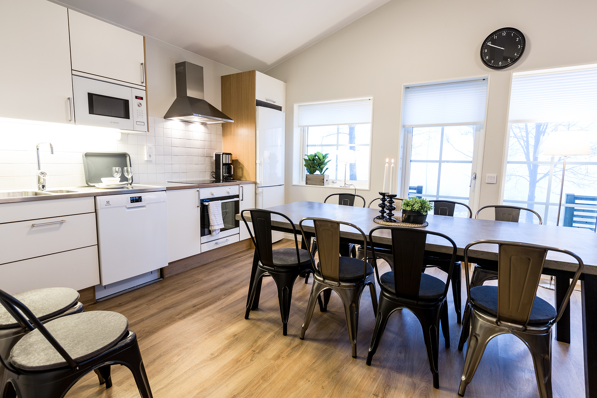 Kitchen with white doors and white walls. Dining room with concrete table and gray metal chairs.