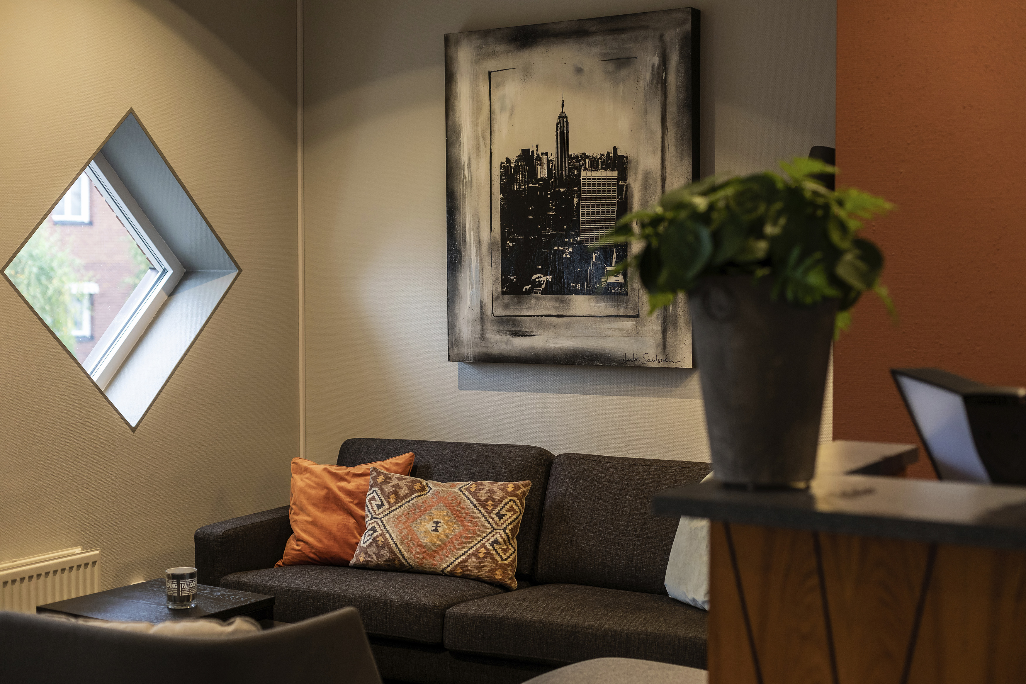 Hotel reception with gray sofas, orange wall behind.