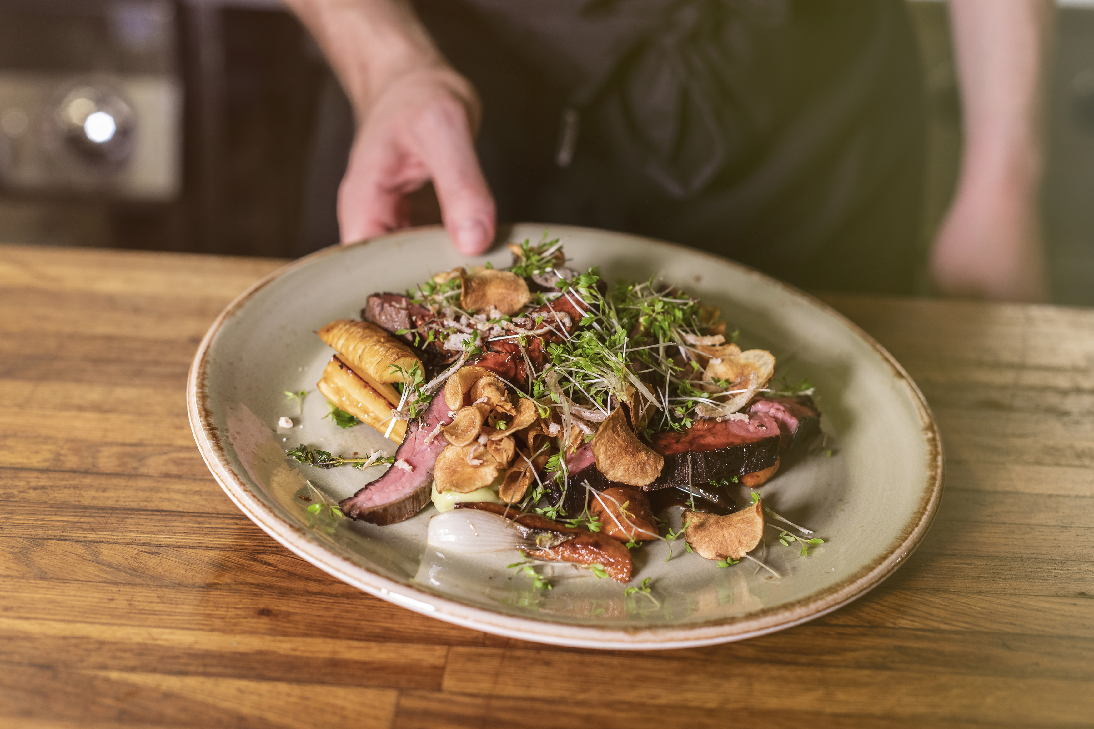 A hand holding up a plate of meat and vegetables.