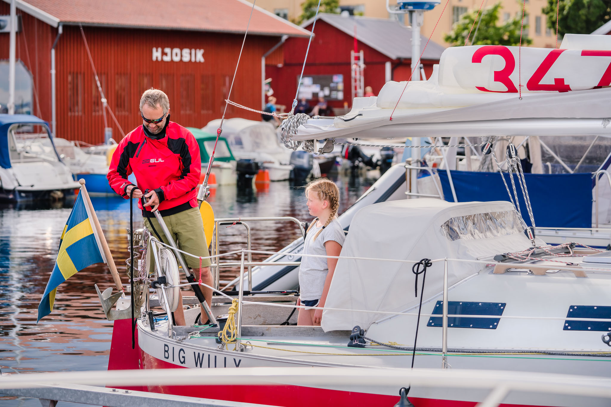 Two people on a sailing yacht in Hjo harbour. 