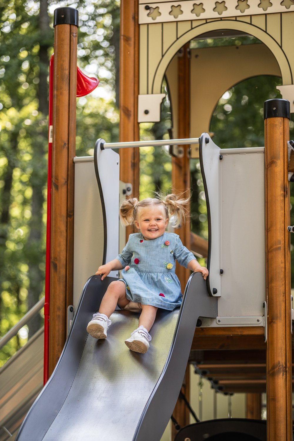 A girl is going down a slide at a playground.