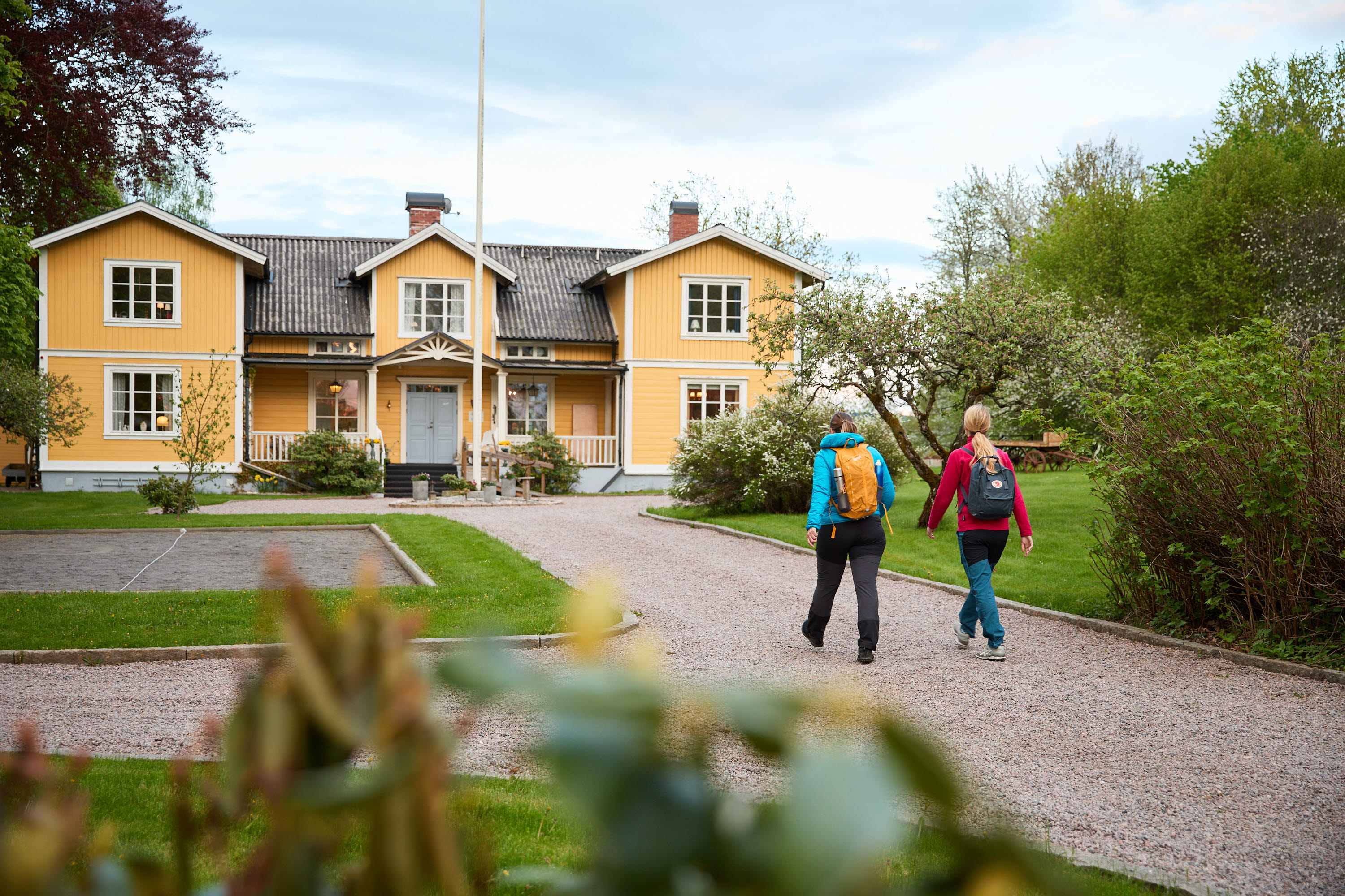 Two hikers are walking towards a yellow B&B.