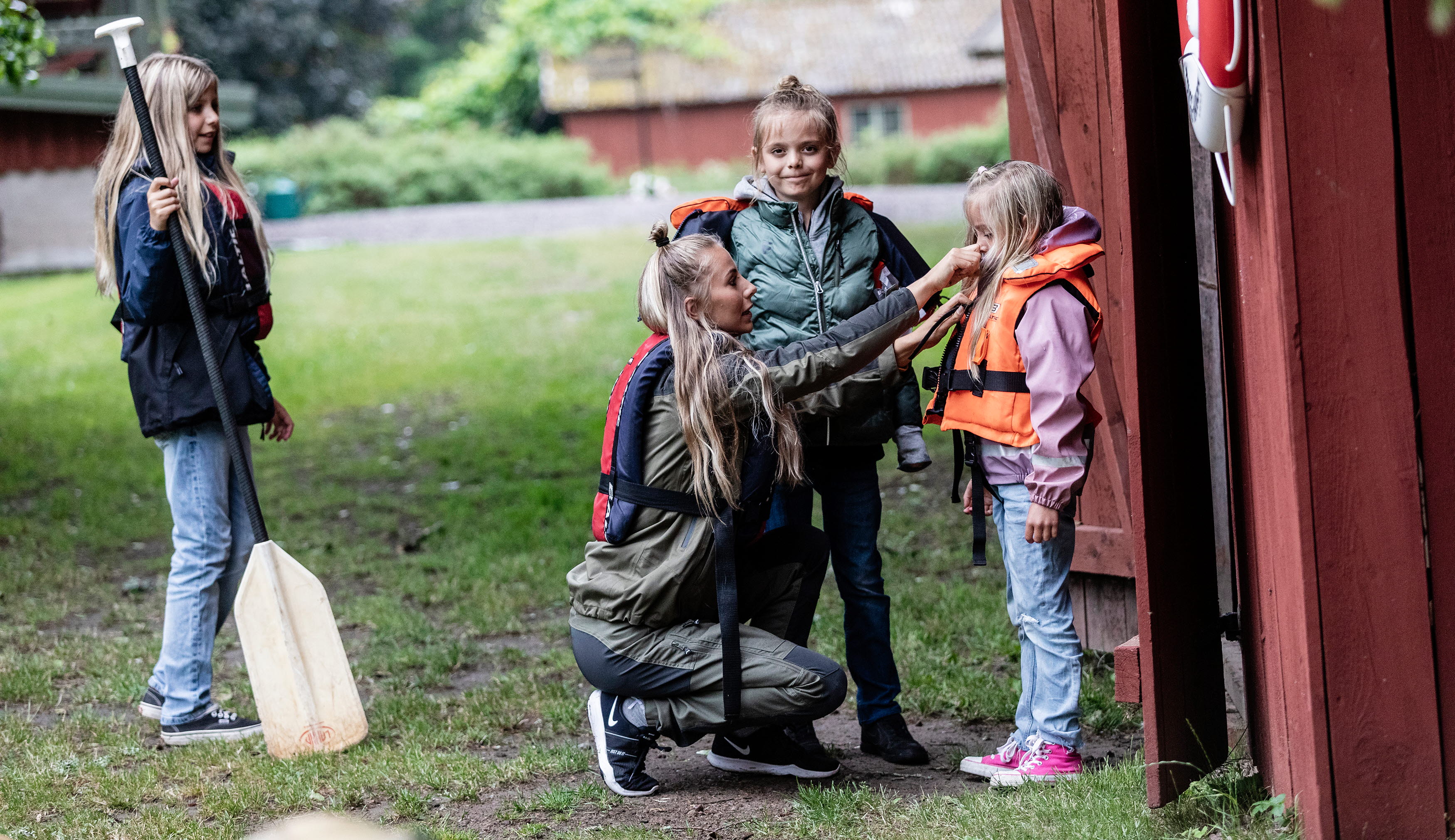 Mother and three children. The mother helps one of the children to put on a life jacket.