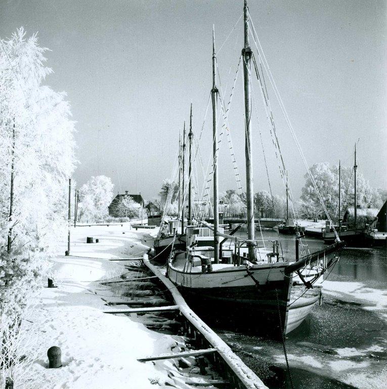 Black and white archive image of the Göta Canal in winter. Snow covers the ground and the trees along the canal.
