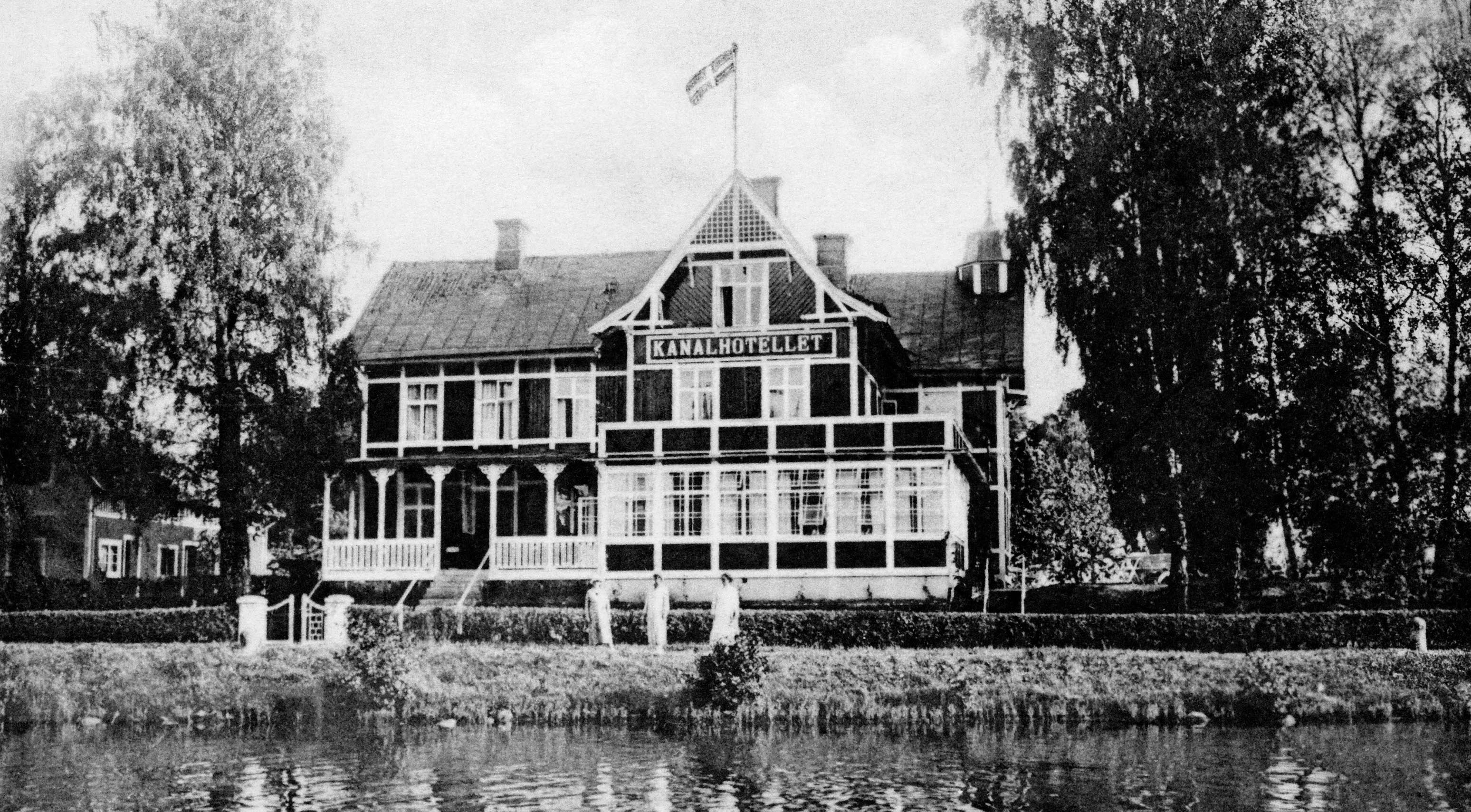 Black and white archive image of a three-story building right next to the Göta Canal.