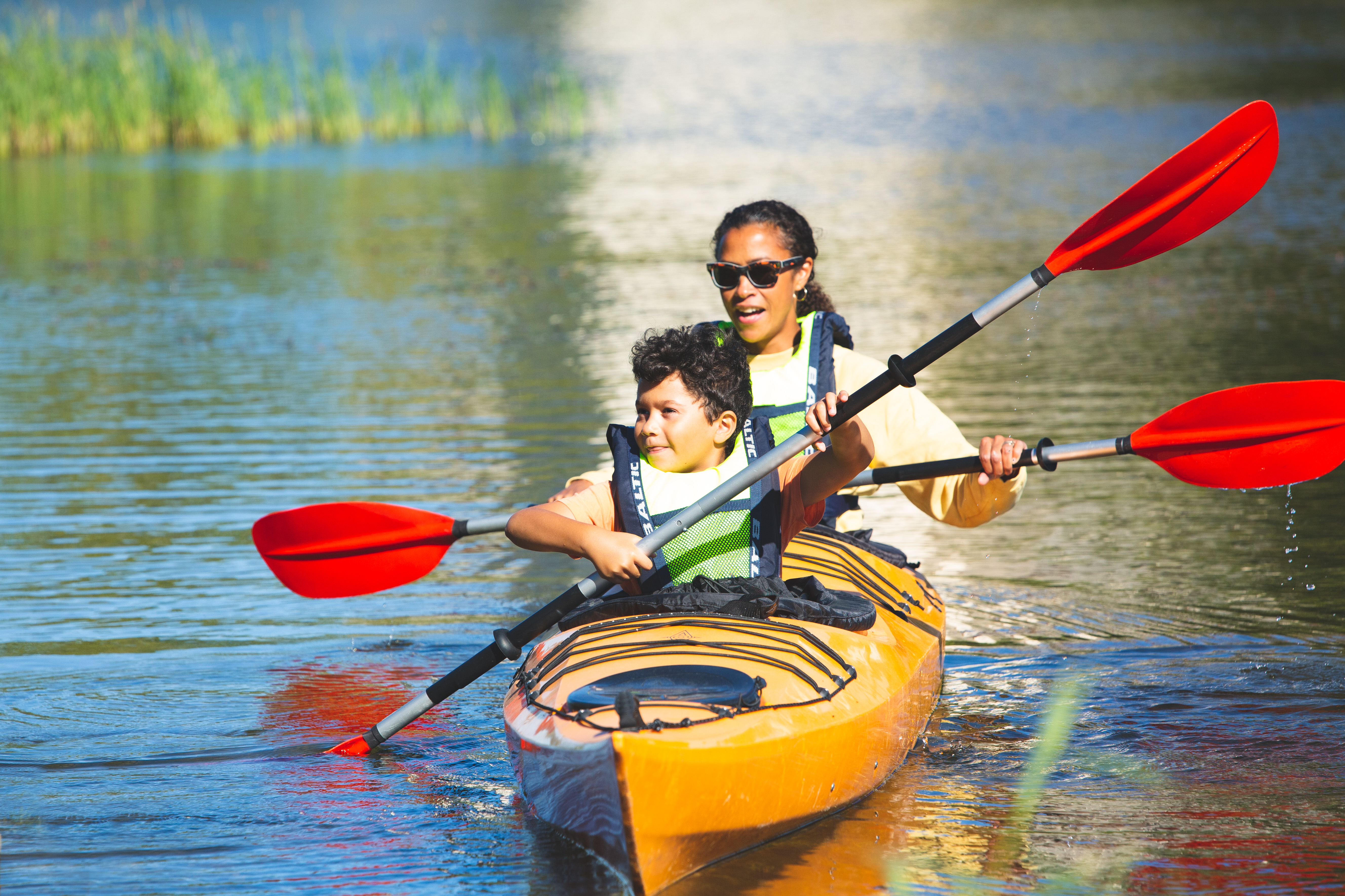 A woman and a child are kayaking.  Water can be seen around them.