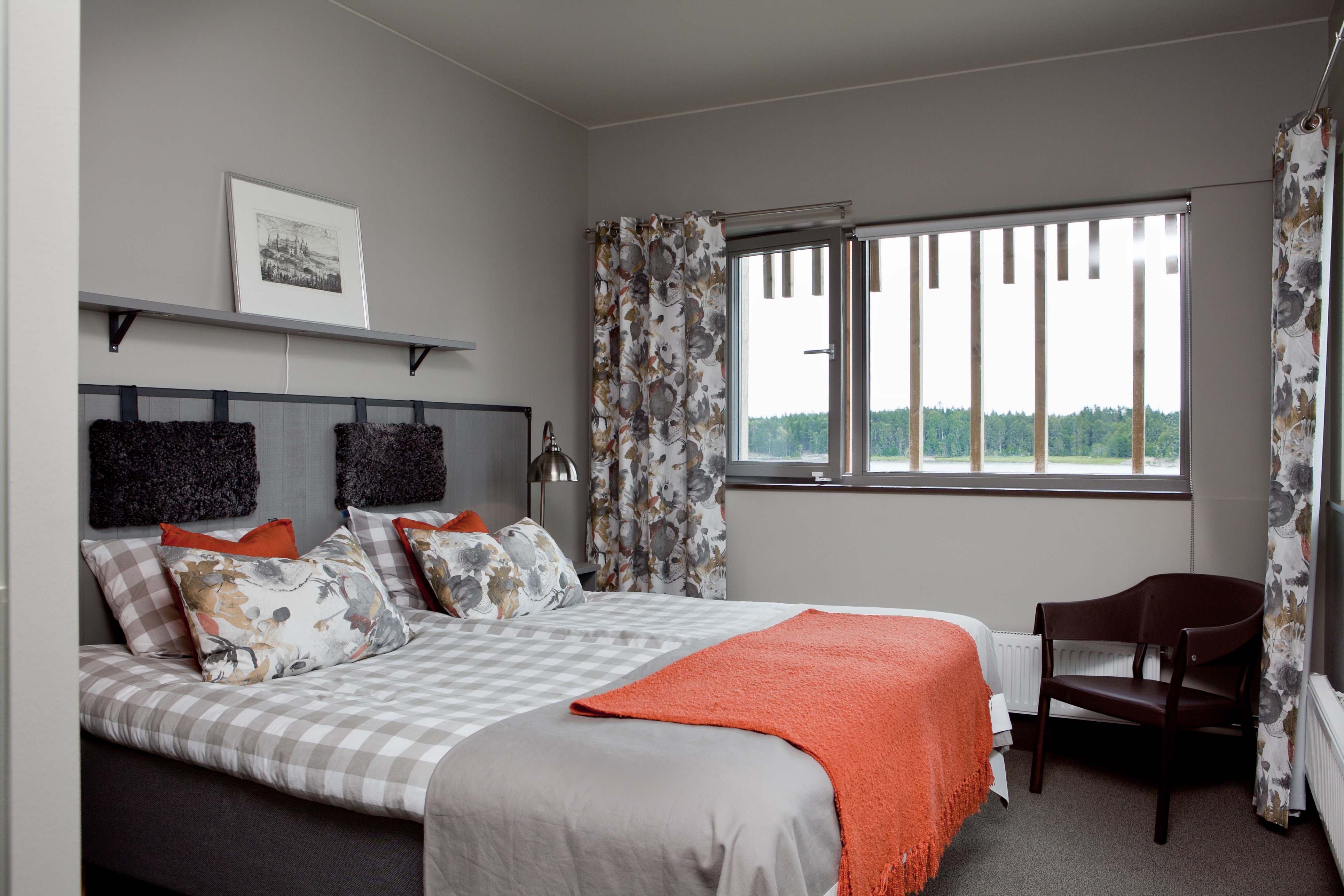 Hotelroom at Naturum. Double bed with checked sheets. Through the window you can see forrest and the lake.