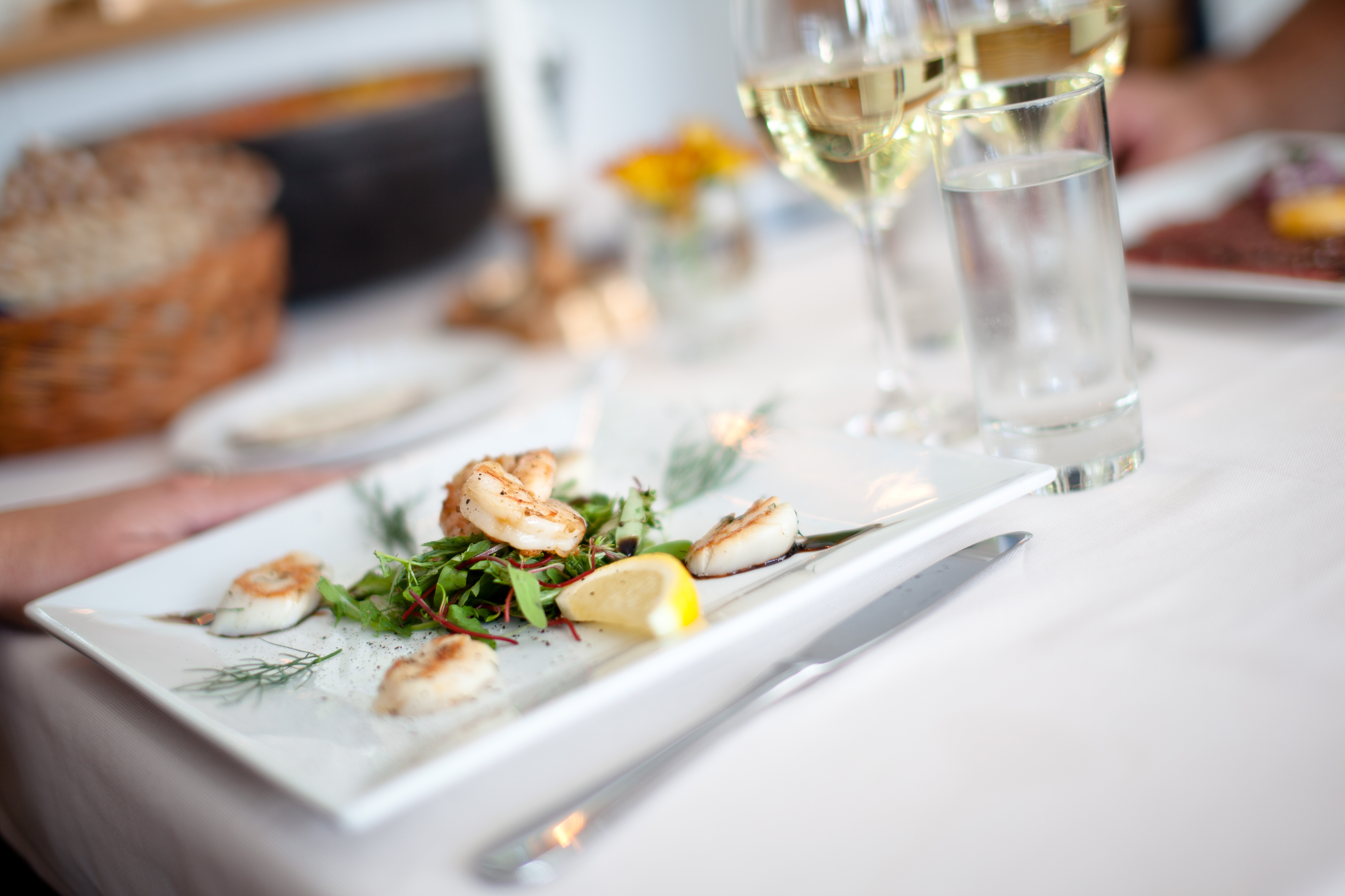 Close up of a plate with nicely presented food. In front of the plate is a glas champagne.