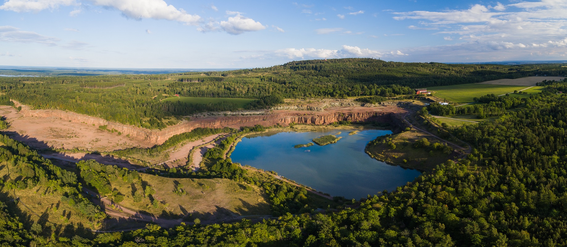 Aerial view of "Stora Stenbrottet" på Kinnekulle. Lake in the middle surrounded by rocks and trees.