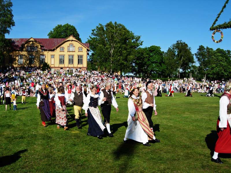 Folkdräktsklädda dansare vid midsommarstången
