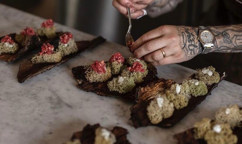 A chef lays out edible delights on a piece of bark.