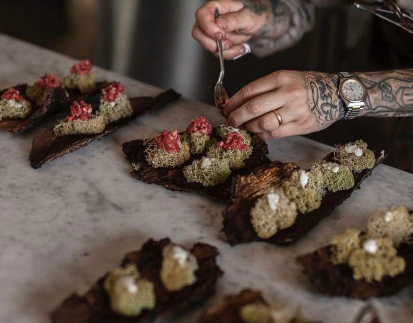 A chef lays out edible delights on a piece of bark.