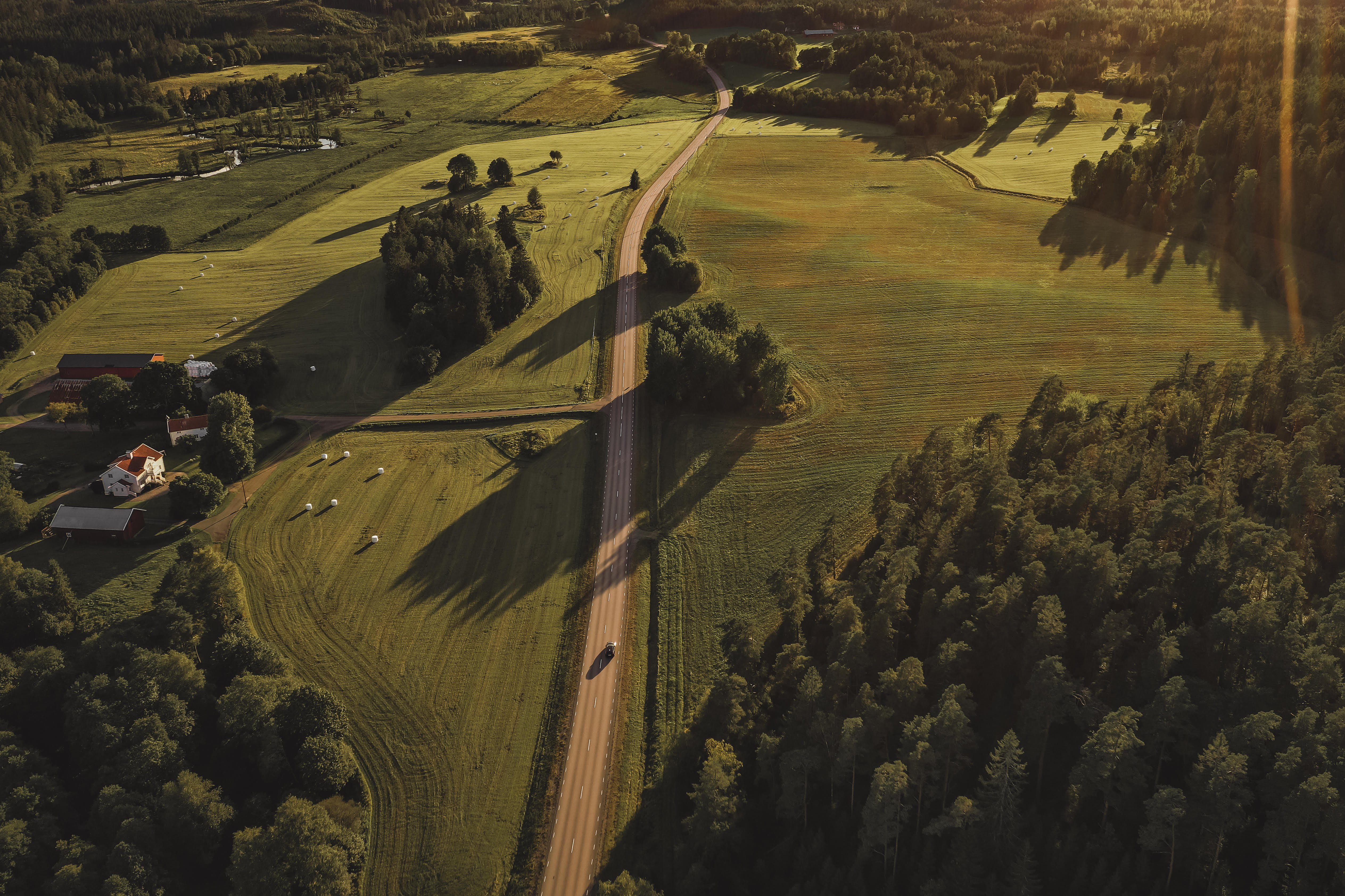 Lanscapepicture from above. Green meadows  with a road in the middle.