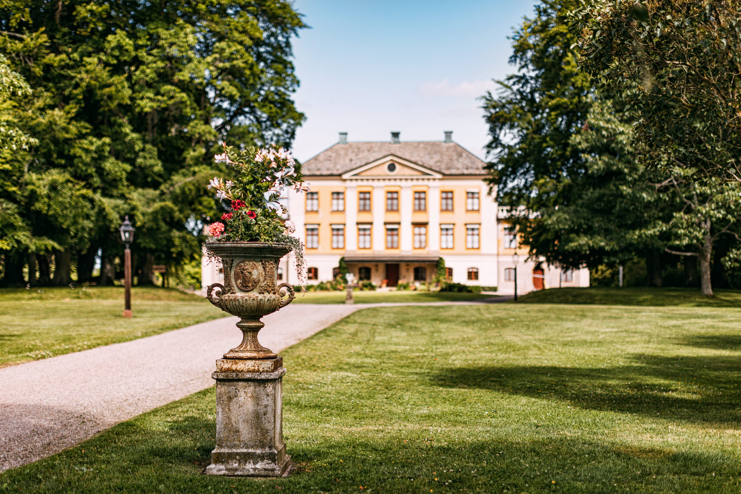 A yellow mansion with large trees at the sides
