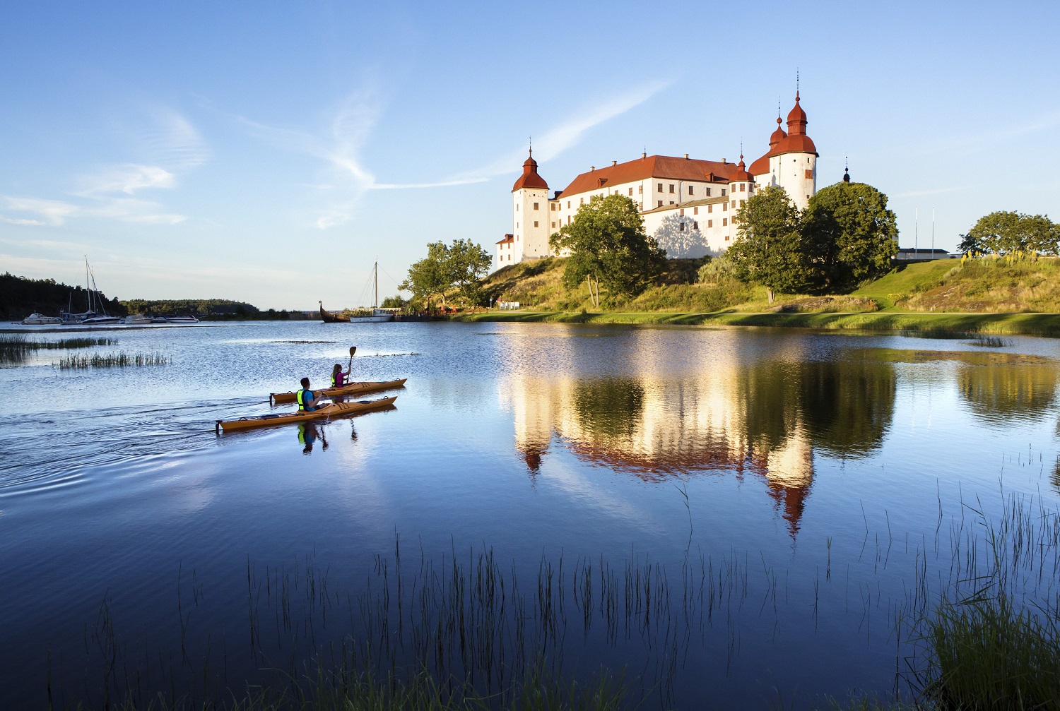 Two people kayaking with Läckö castle in the background.
