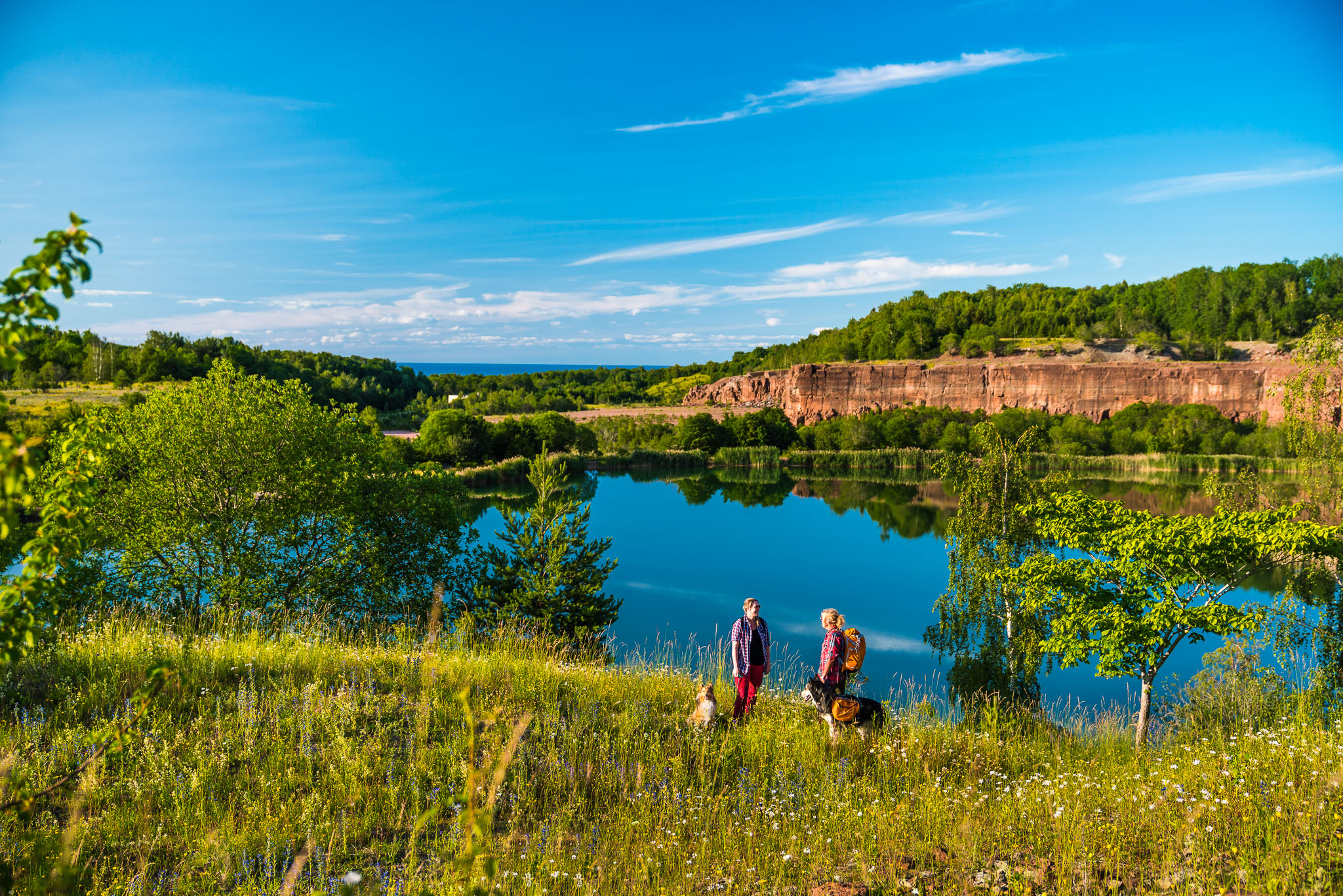 Two women are walking with their dogs and have just taken a break from a large quarry.