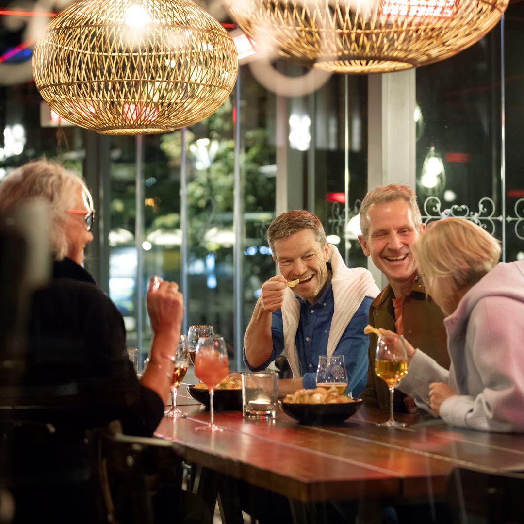 Two men and two women are eating on a restaurant, having a good time. 