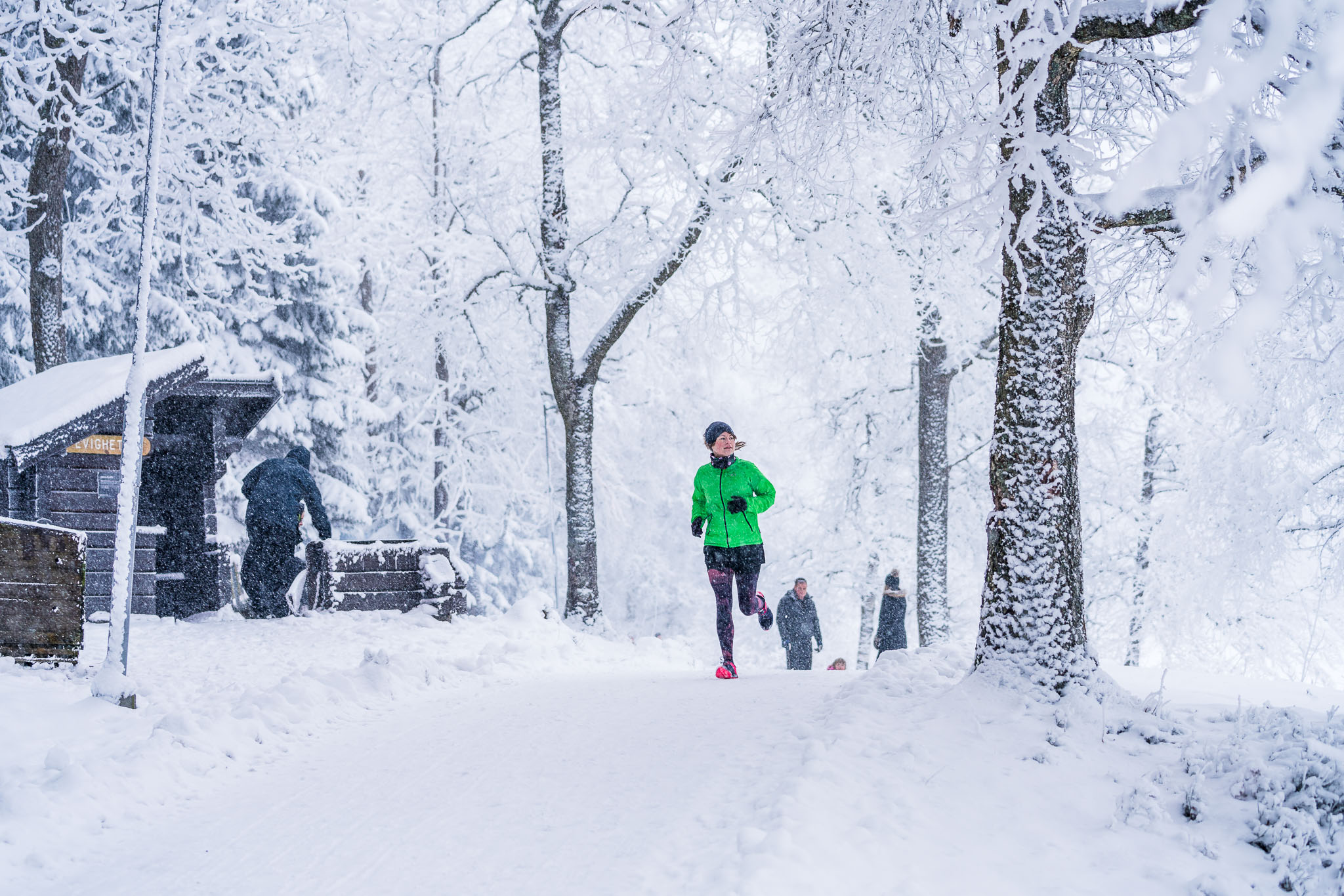 Women in a green jacket runs through a breathtaking white winter landscape 