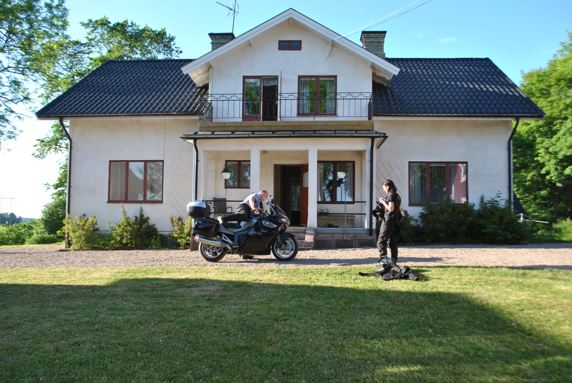 2 people standing outside Berglunda hostel with a motorcycle.