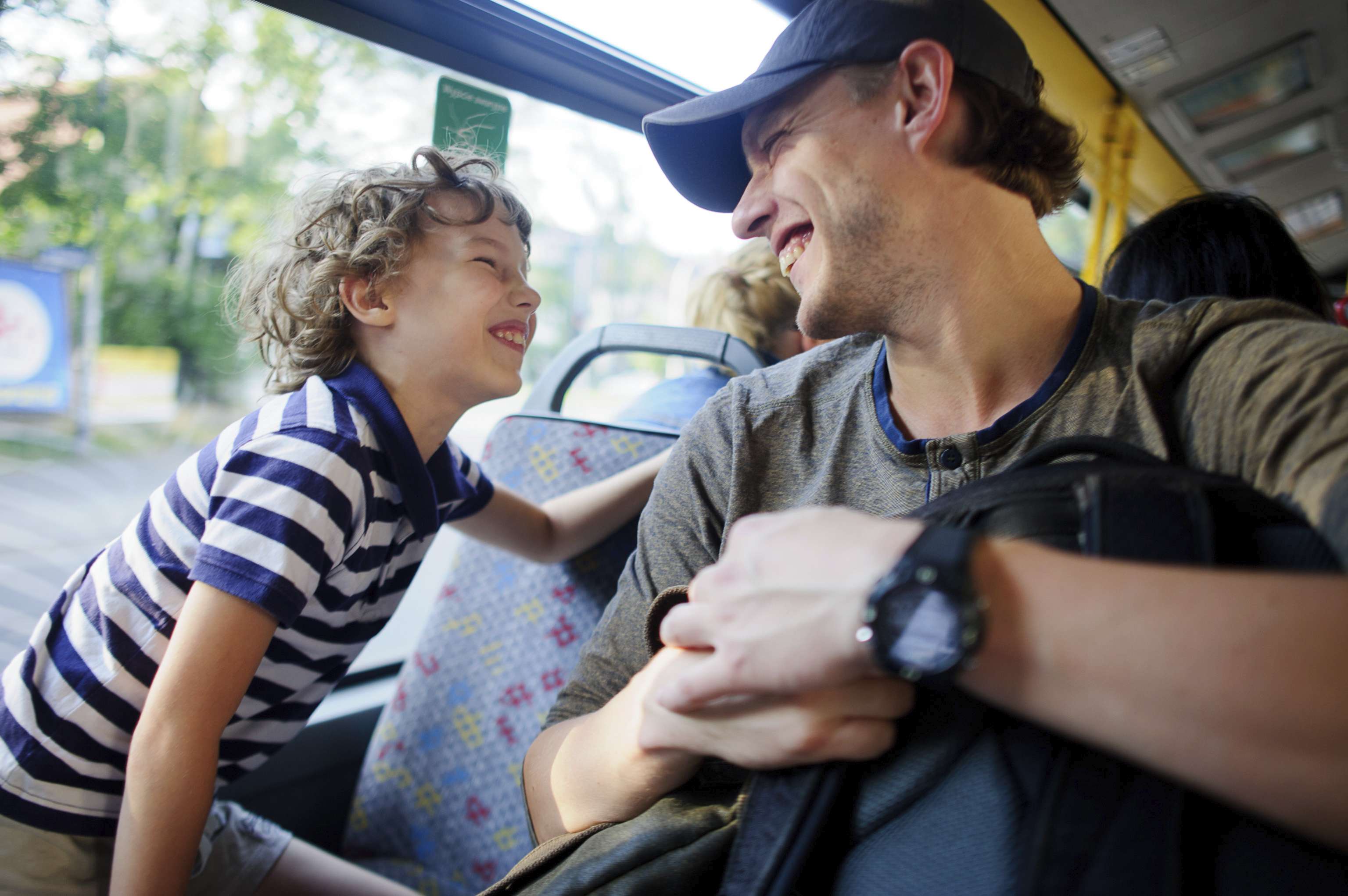 Happy laughing young boy with dad on a bus