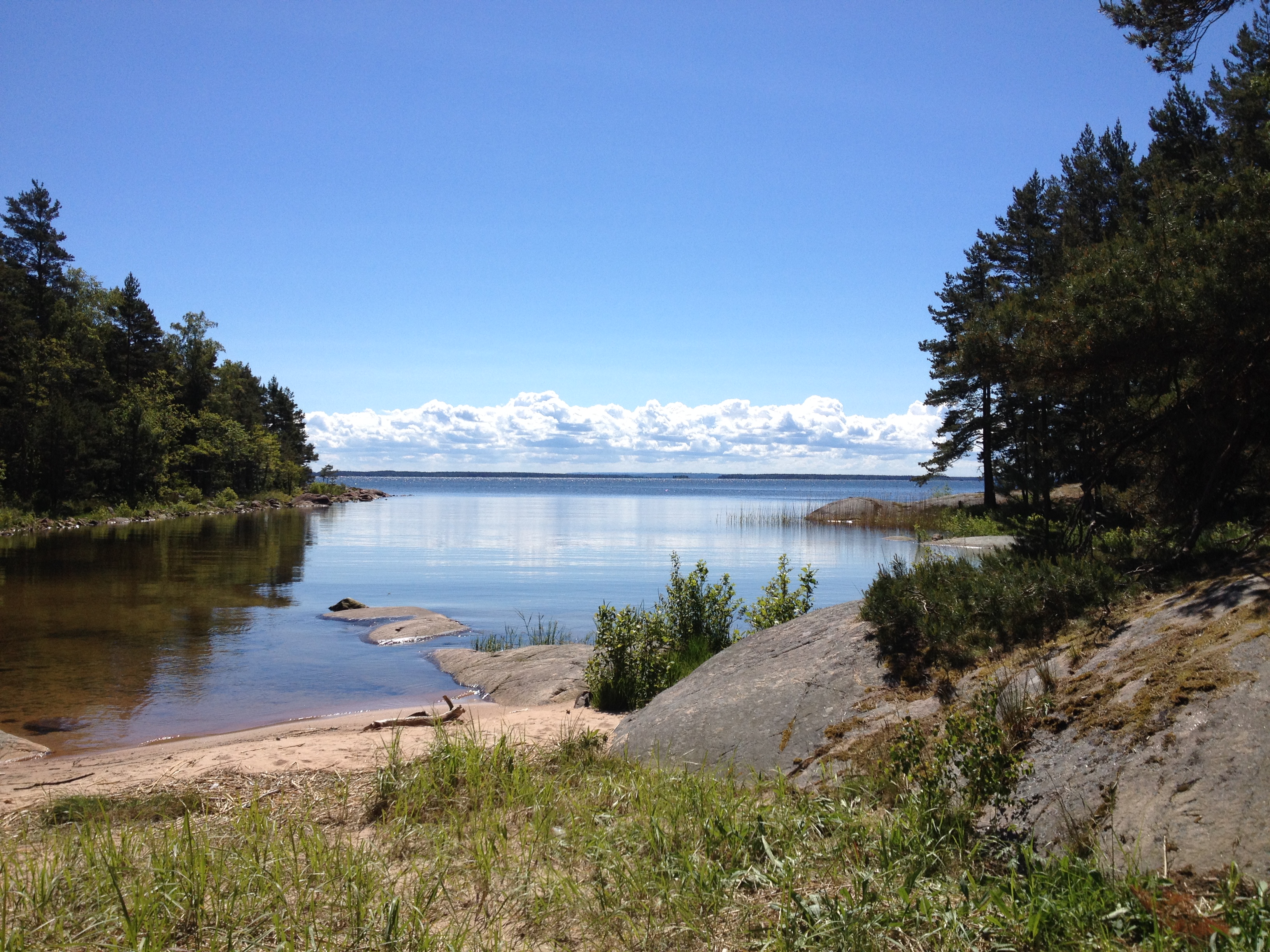 Beautiful view of a rocky beach. The water lies still under a clear blue sky.