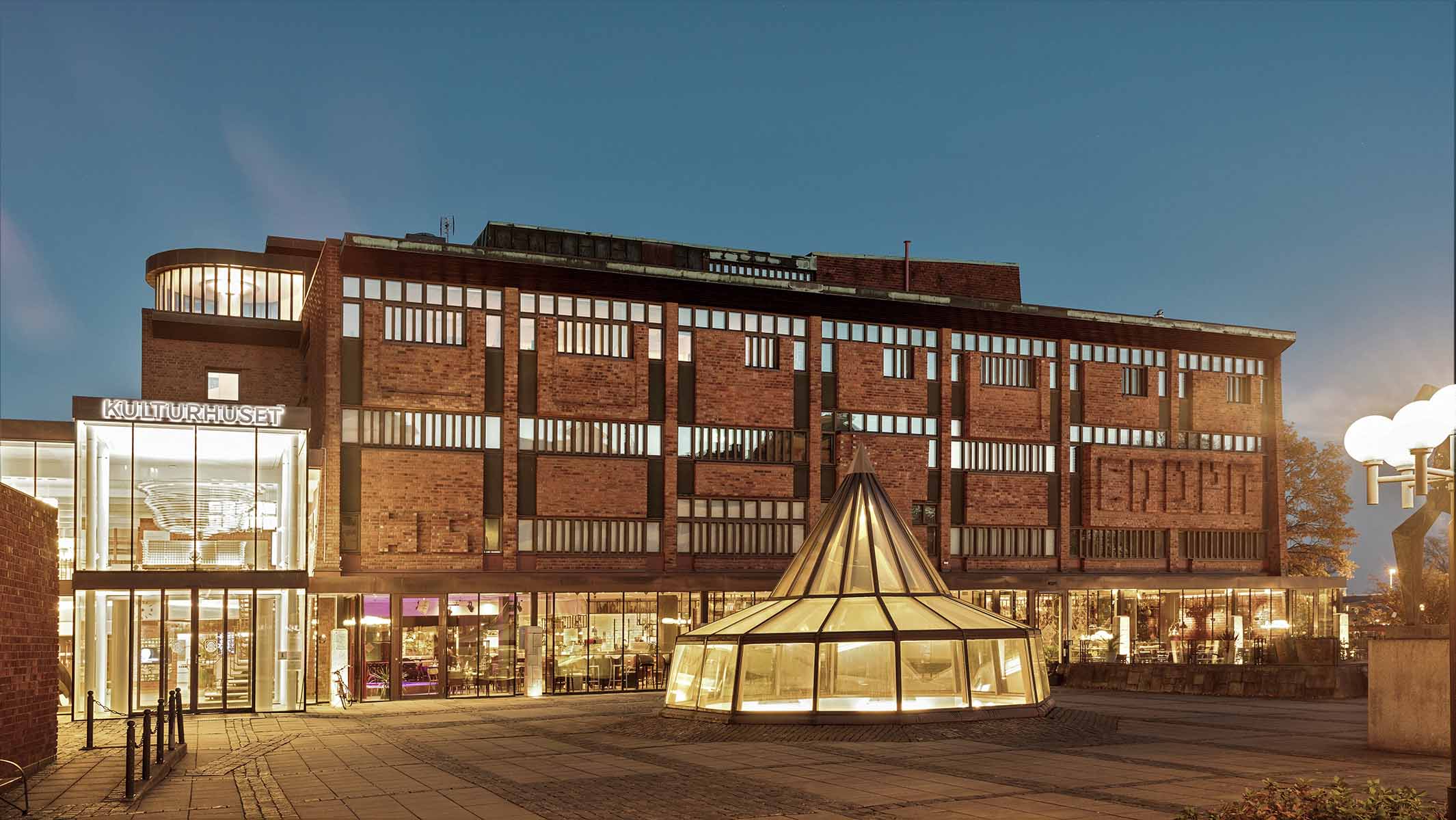 House of Culture in Skövde by night. A warm glowing light is shining in the dark from every window. 